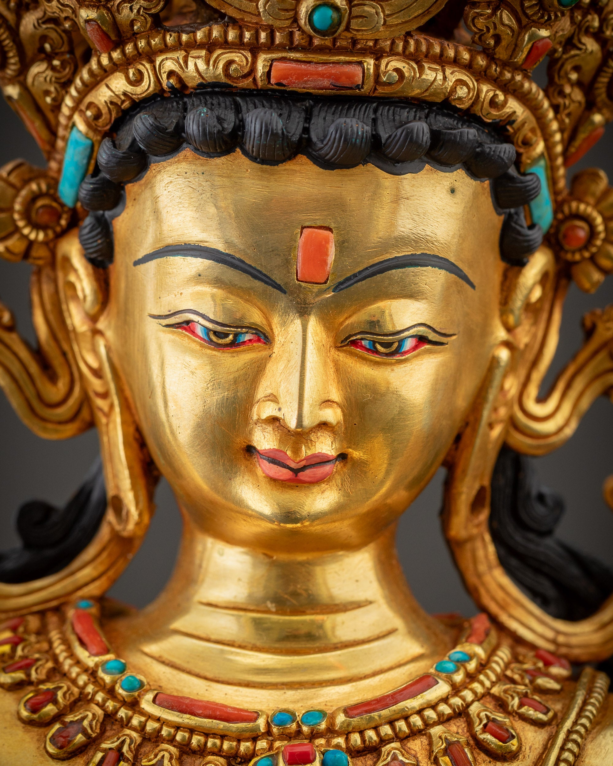 Detailed close up face of Maha Manjushri statue showing peaceful expression and gold gilding.
