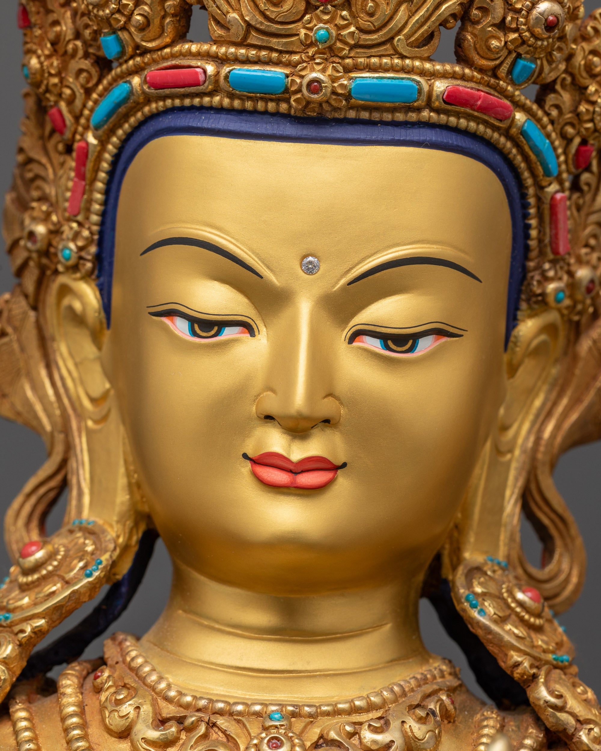 Detailed close up face of Manjushri Buddha with serene expression and gold-gilded features
