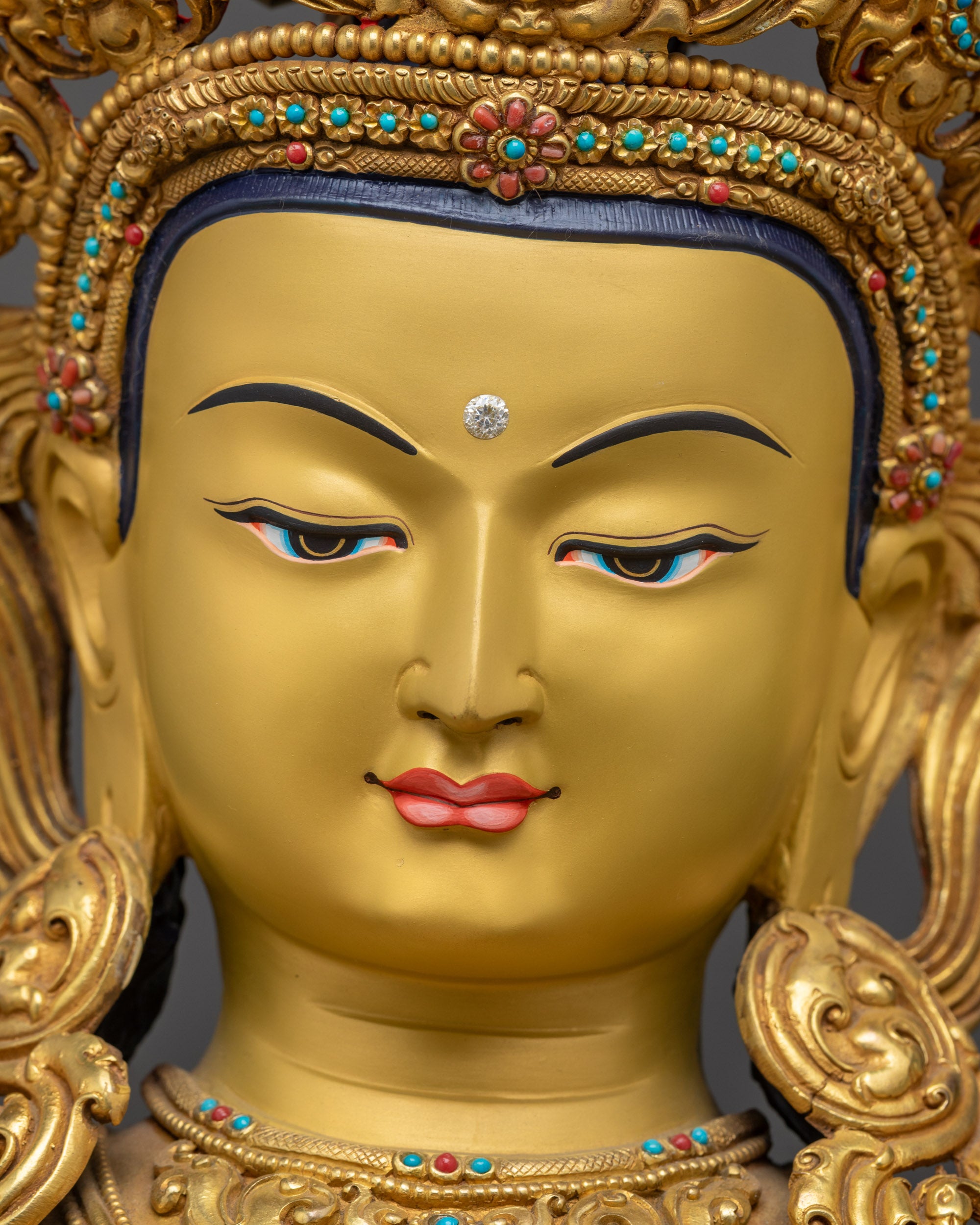 Detailed close up face of Manjushri Sculpture with gold-gilded face and crown
