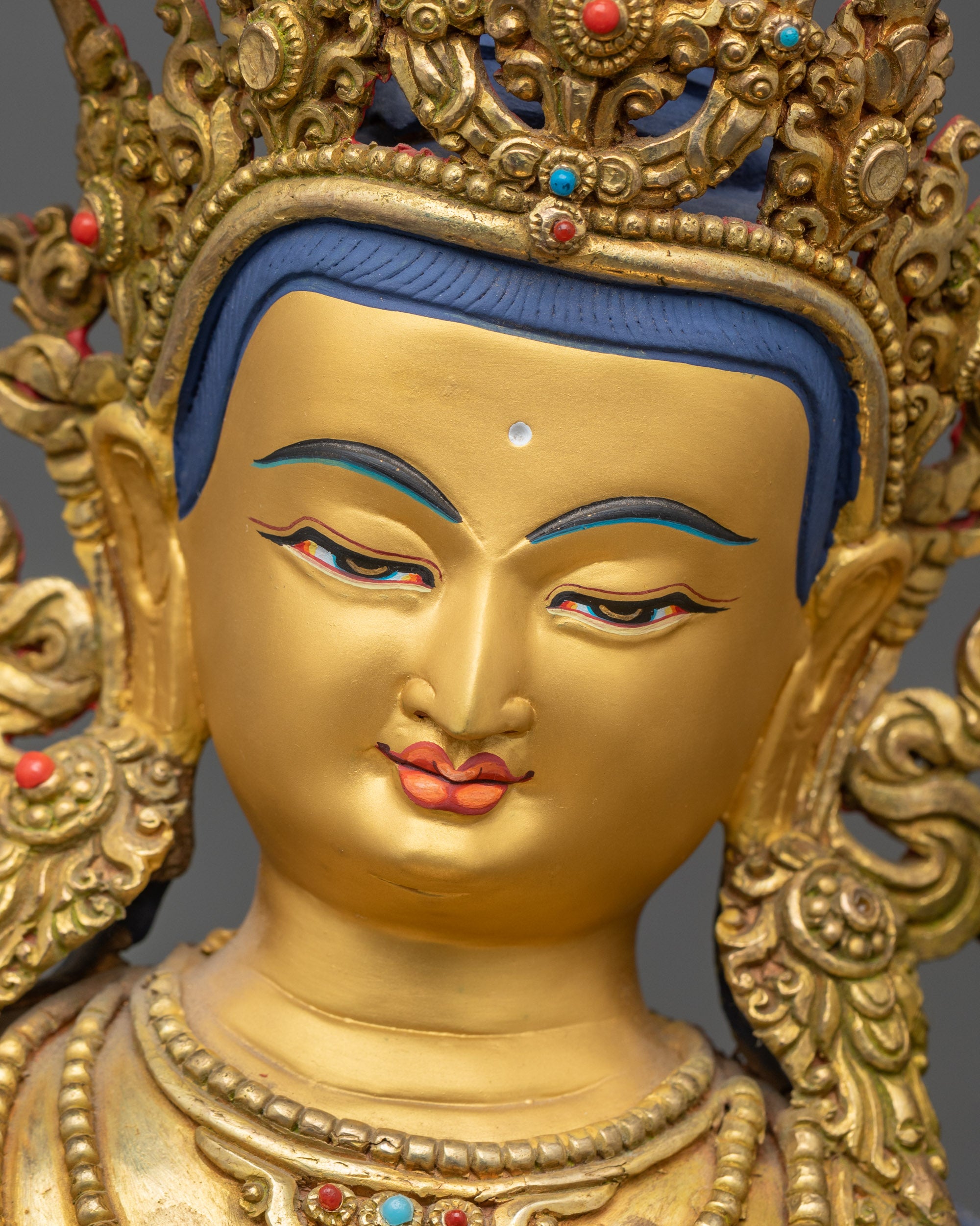 Detailed close up face of Manjushri statue with serene gold-painted expression