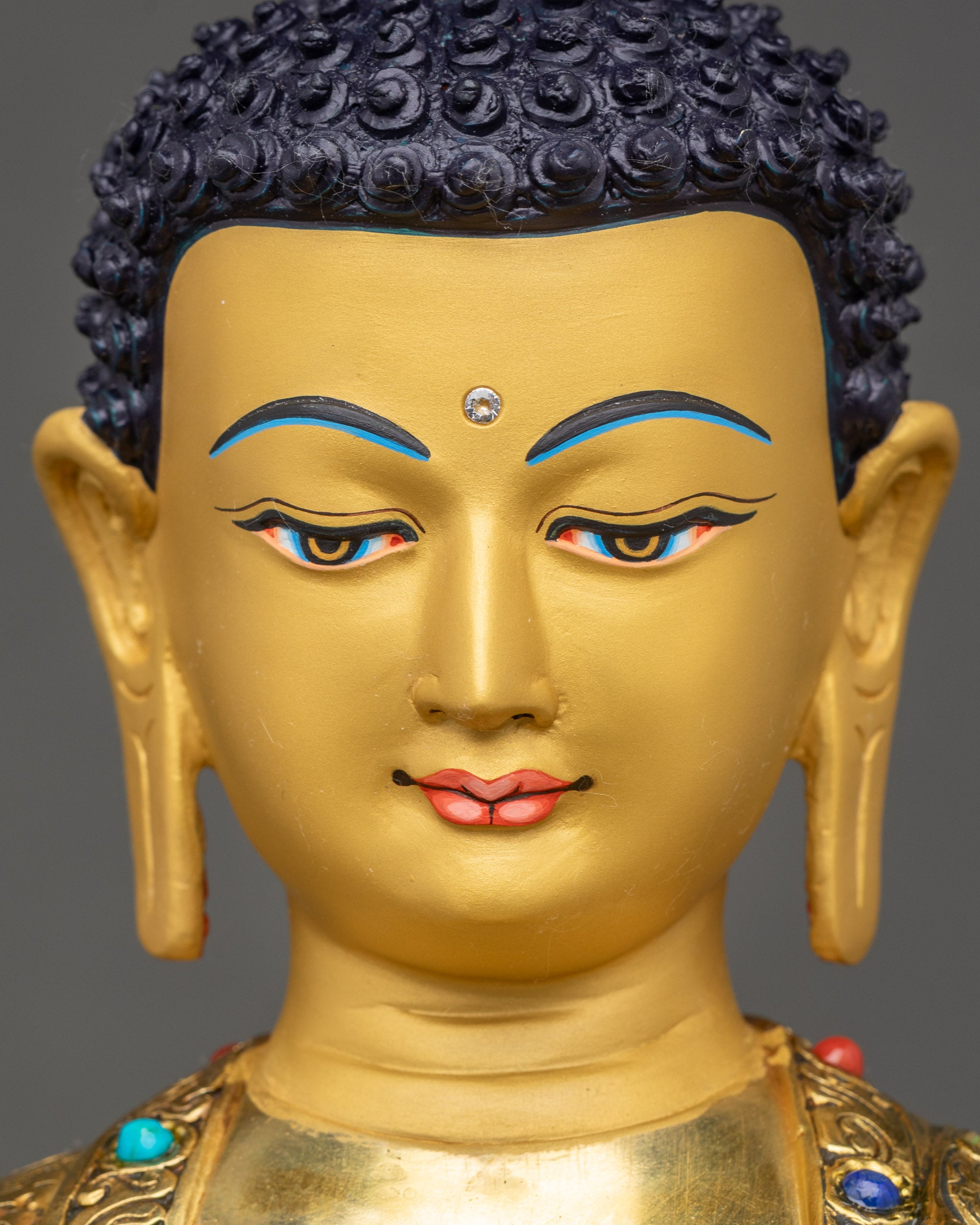 Detailed close up face of Medicine Buddha with gold-gilded features and serene expression