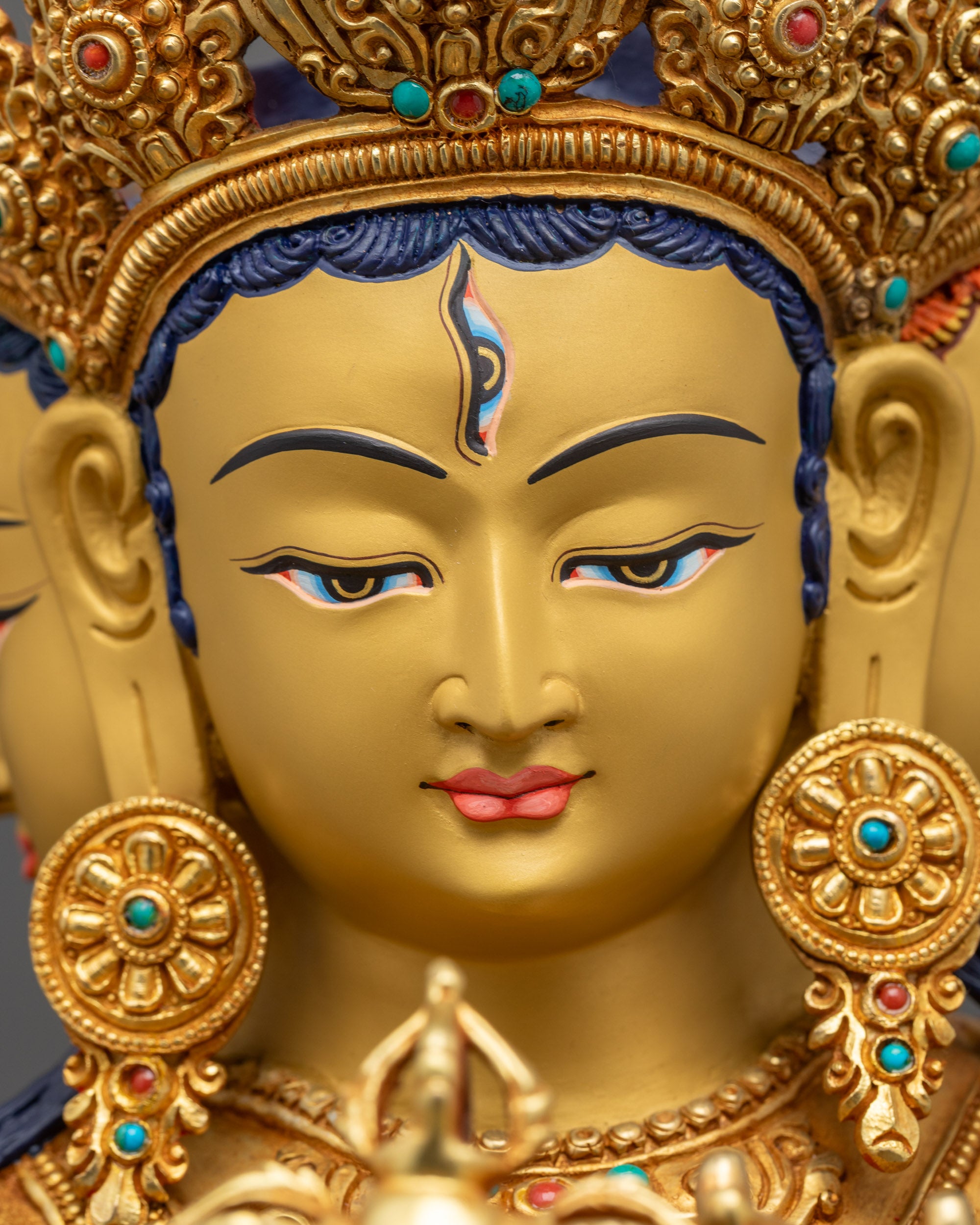 Detailed close up face of Namgyalma Ushnishavijaya statue showing third eye and gold-gilded face