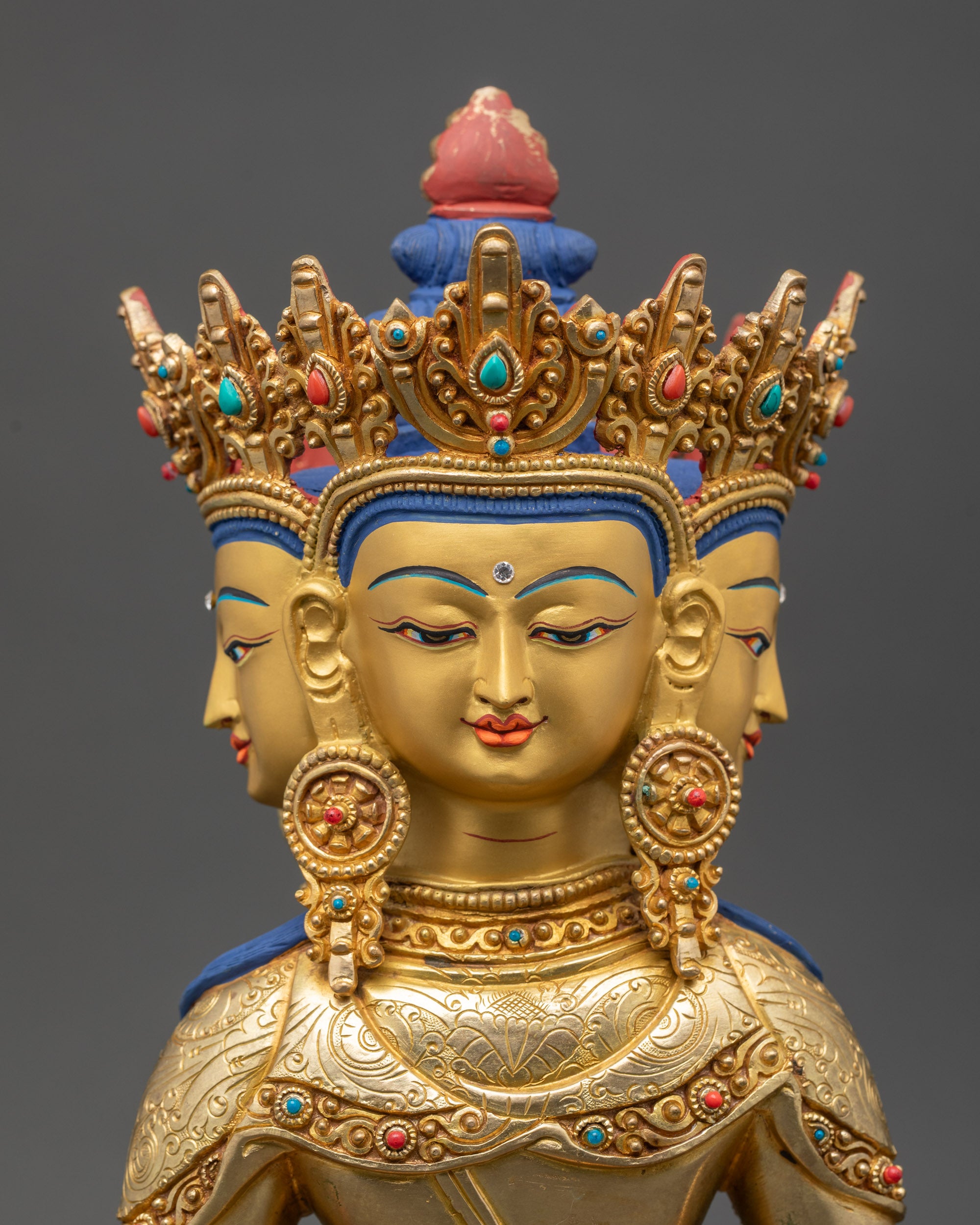 Detailed close up face of Vairocana Buddha with gold-gilded back faces and semi-precious crown