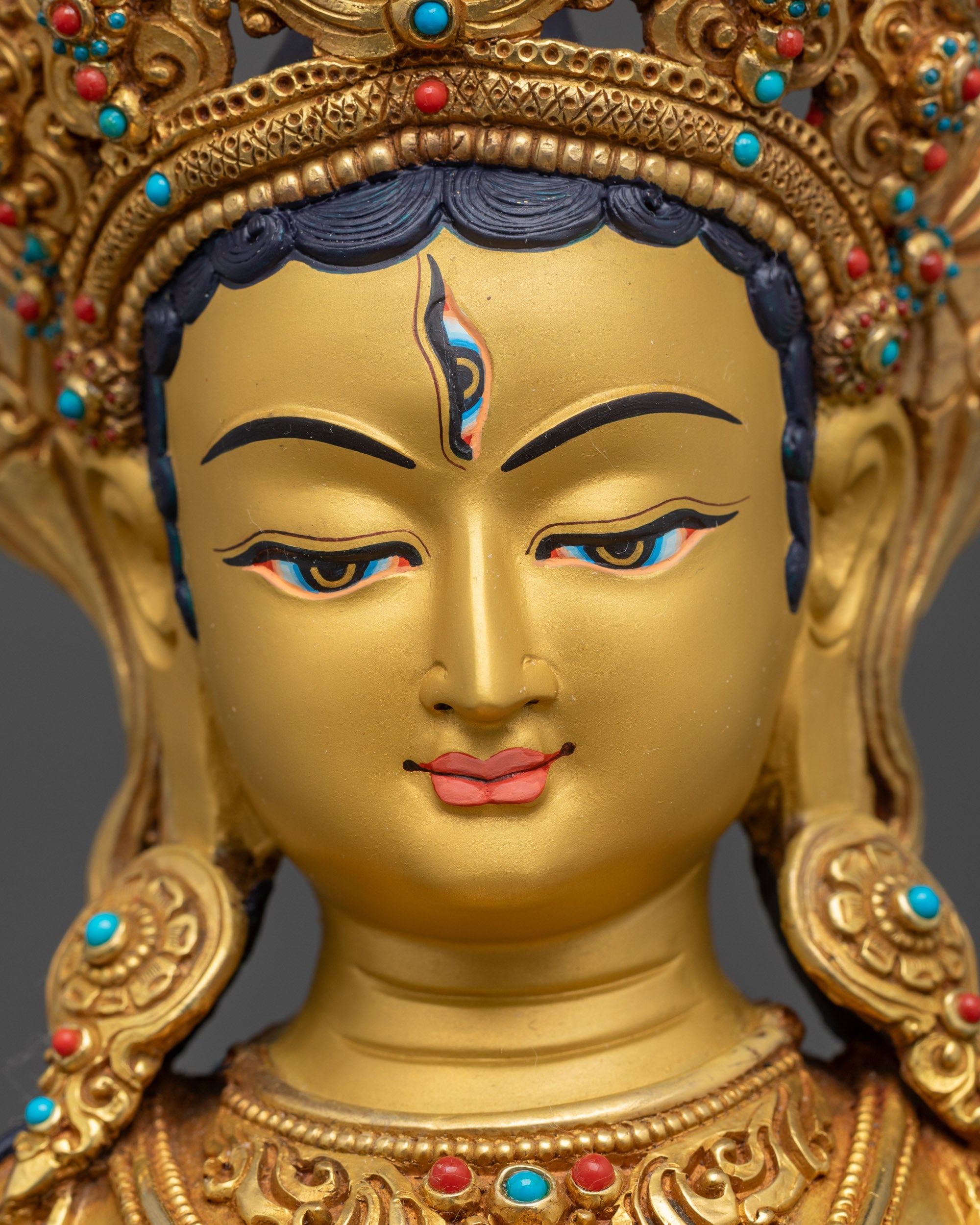 Detailed close up face of White Umbrella Dukar Statue with third eye and gold gilding
