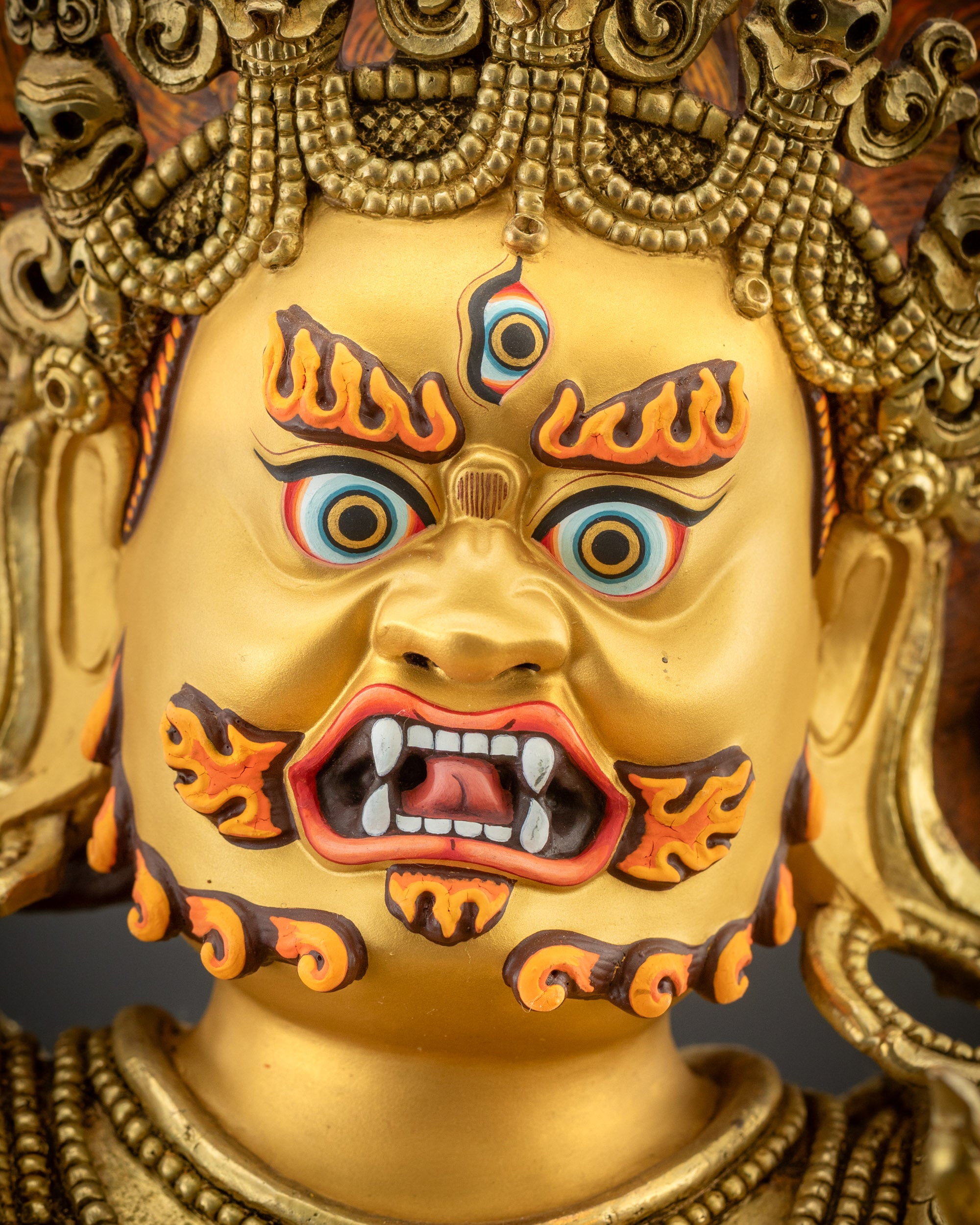 Detailed close up face showing piercing eyes, mustache, and gold-gilded face
