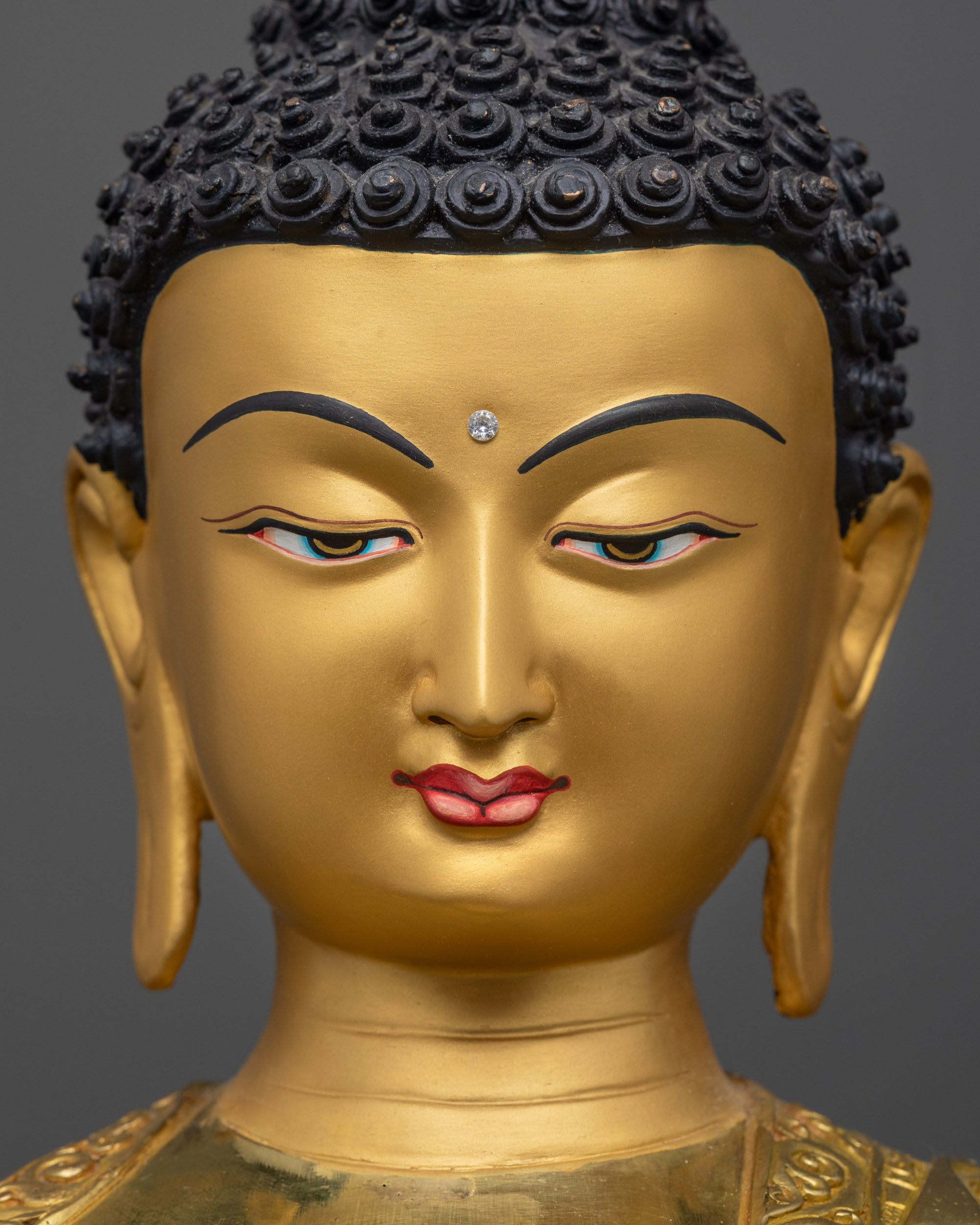 Detailed close up of Buddha Mitrugpa face with tranquil expression and gold-gilded finish
