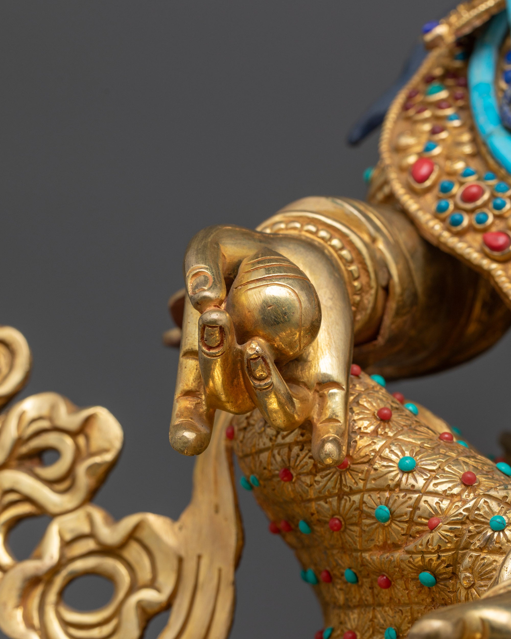 Detailed close up of Dzambhala holding jewel-shaped citron fruit with gold-gilded accents
