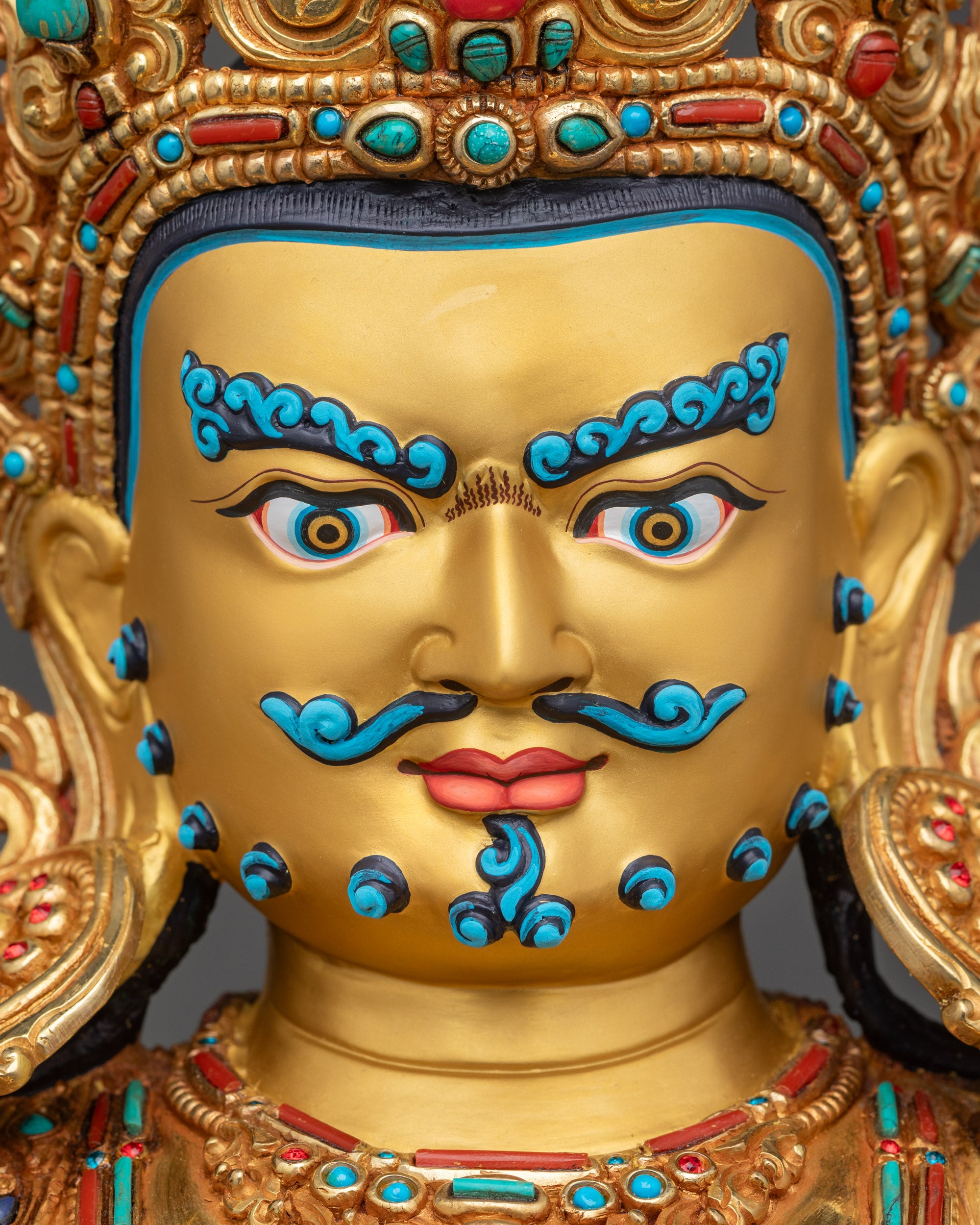 Detailed close up of Dzambhala wrathful gold painted face with expressive sacred features