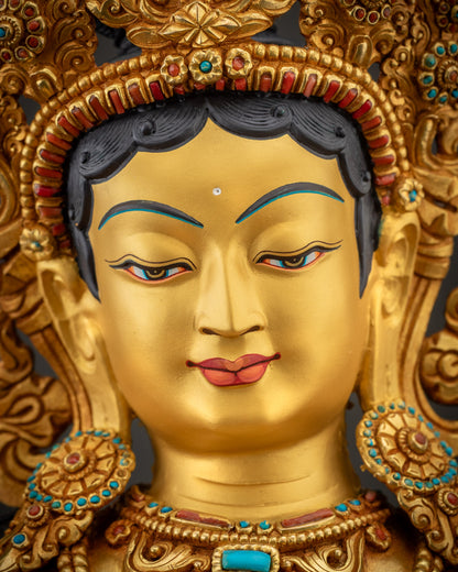 Detailed close up of Green Tara face showing serene expression and gold gilding
