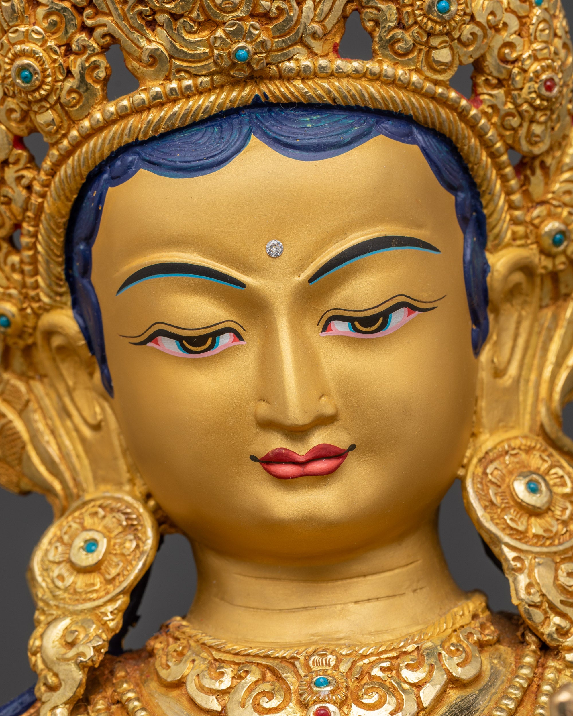 Detailed close up of Green Tara face with five-jeweled crown and tranquil expression
