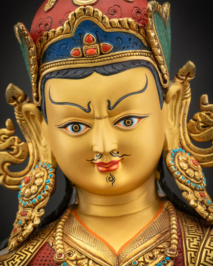 Detailed close up of Guru Rinpoche face with semi-wrathful expression and gold gilded finish