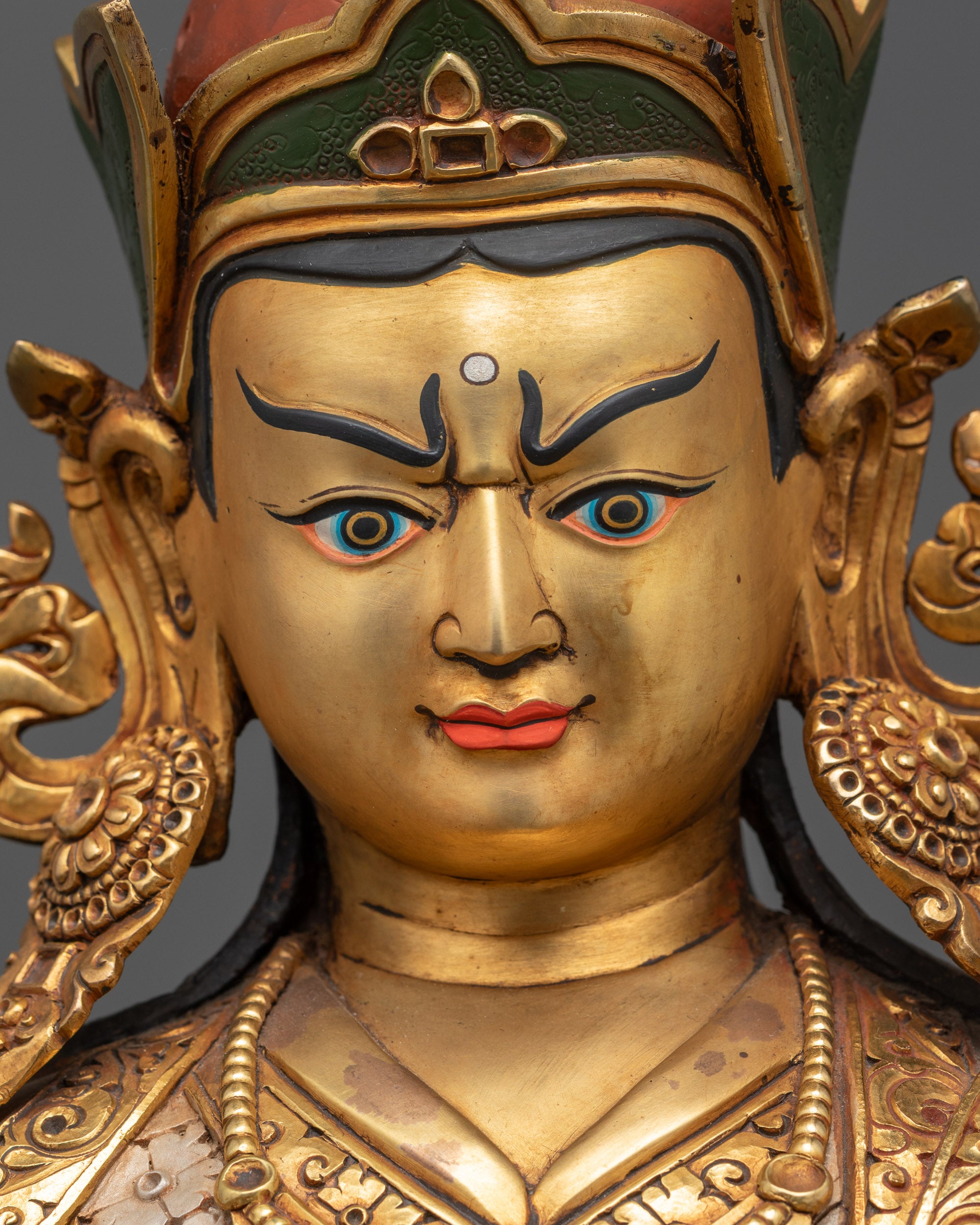 Detailed close up of Guru Rinpoche semi-wrathful Fire Gold-gilded face with crown and jewelry
