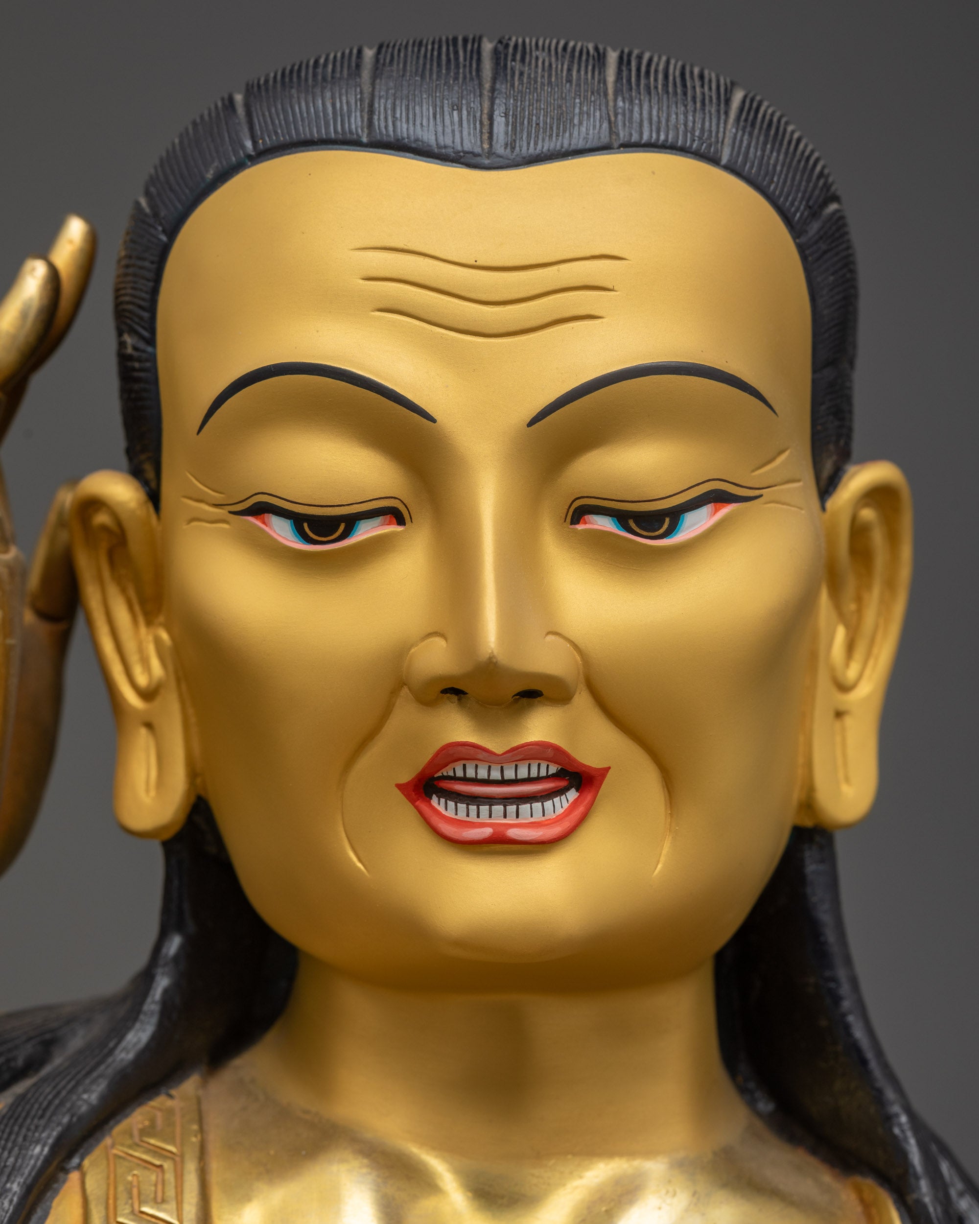 Detailed close up of Milarepa gold-gilded face with semi-wrathful listening expression

