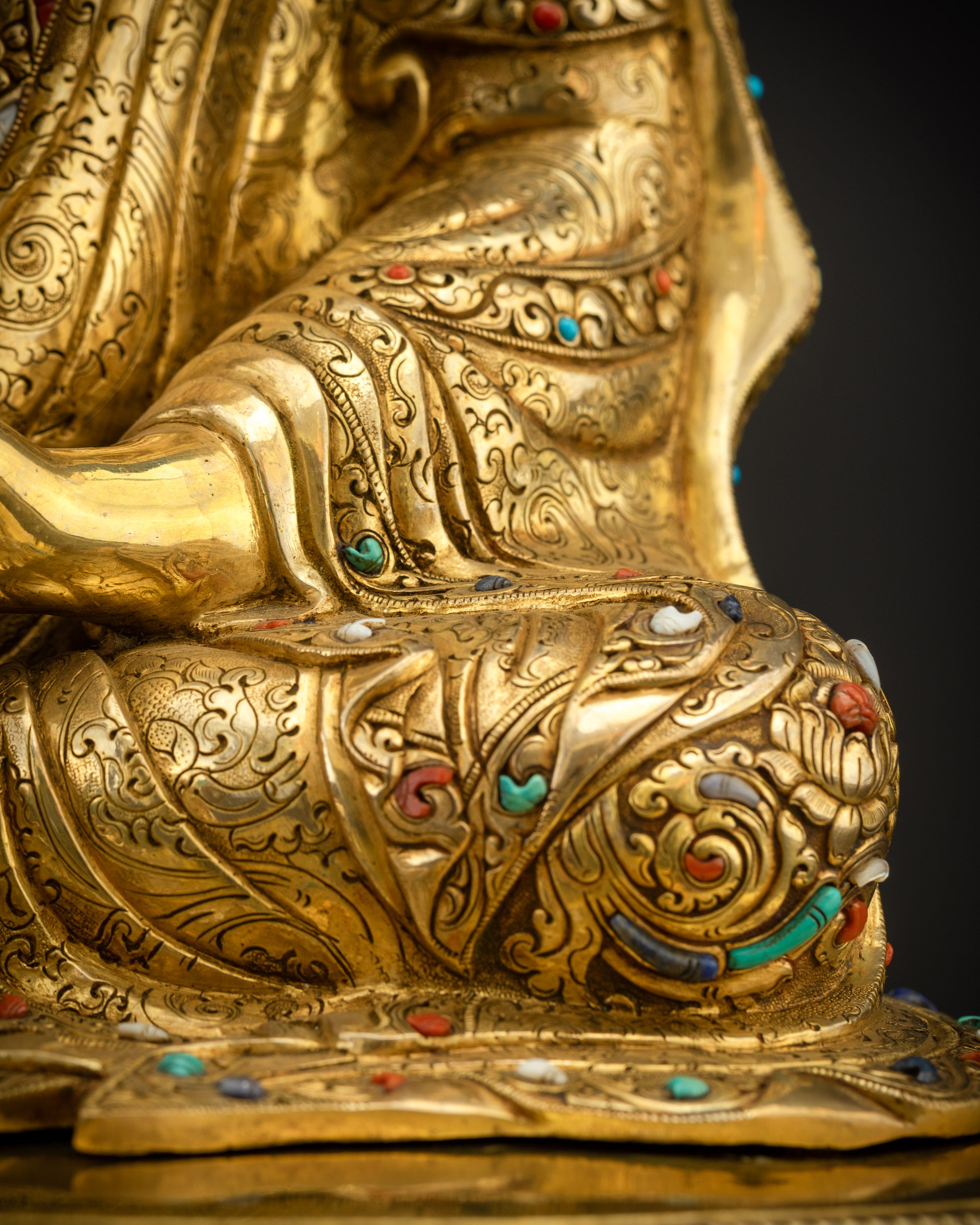 Detailed close up of kasaya robe showing intricate carving and gemstone accents
