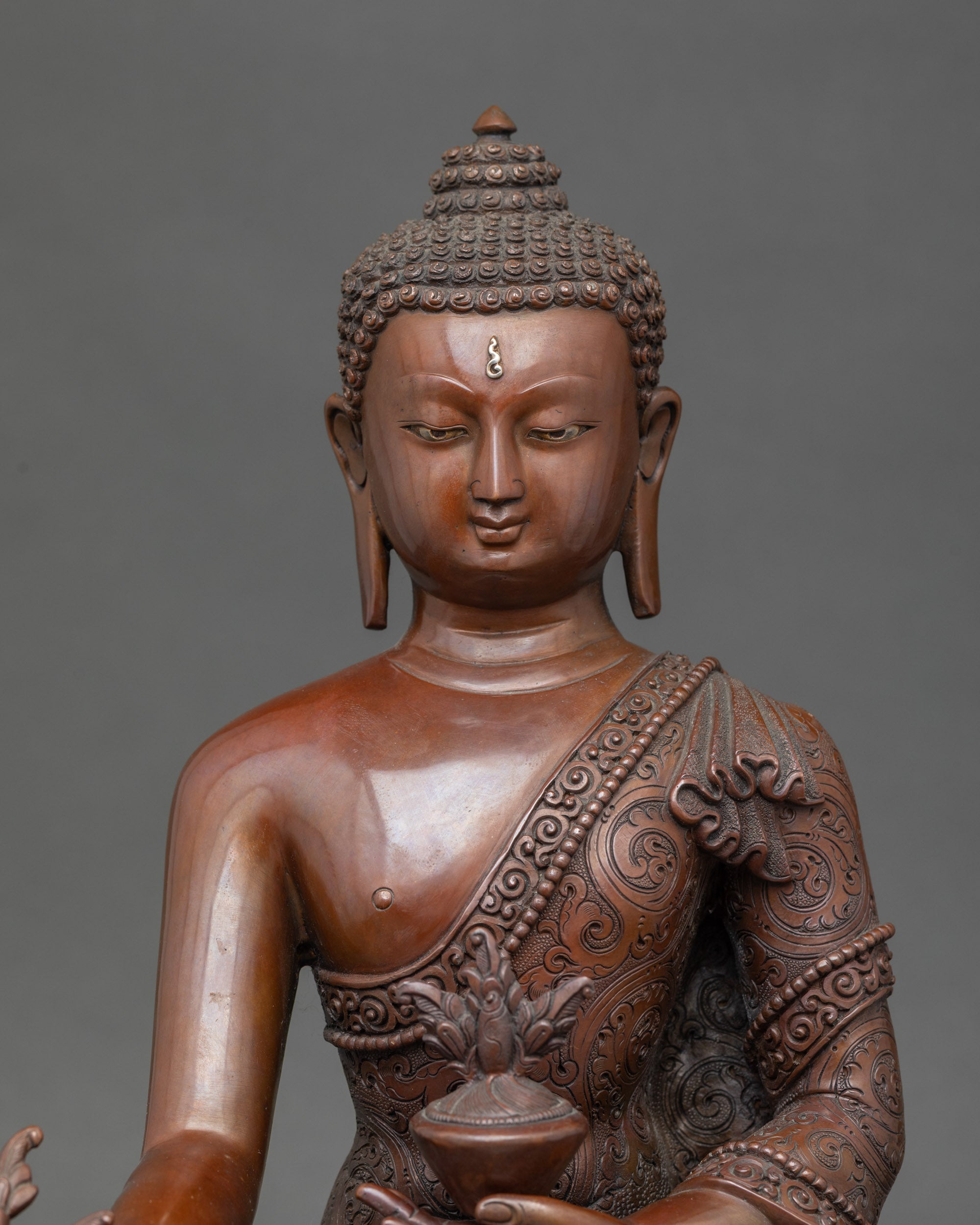 Detailed face of Medicine Buddha statue, oxidized Nepalese copper, spiritual healing deity