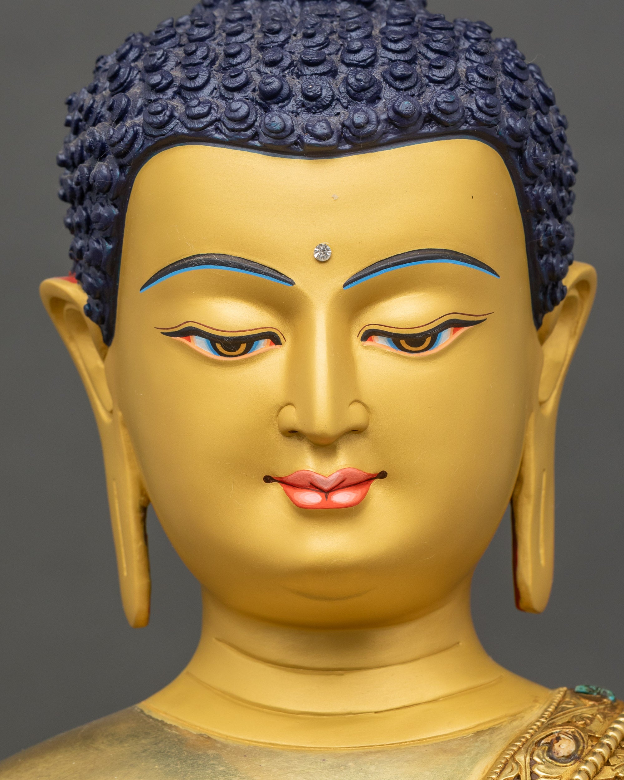 Detailed face of Shakyamuni Buddha, gold-painted, serene eyes and smiling expression