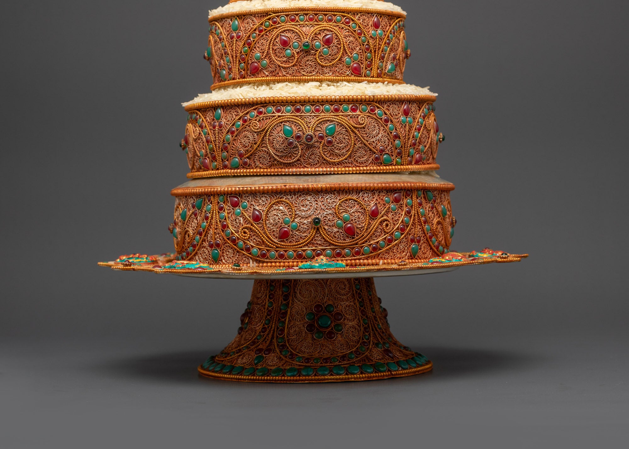 Detailed filigree work and semi-precious stones like ruby, turquoise, and emerald on Tibetan Ratna Mandala