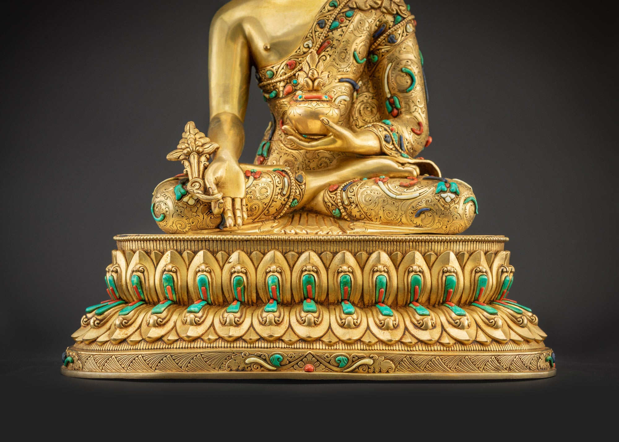 Detailed landscape shot front of Medicine Buddha seated on lotus showing full golden body