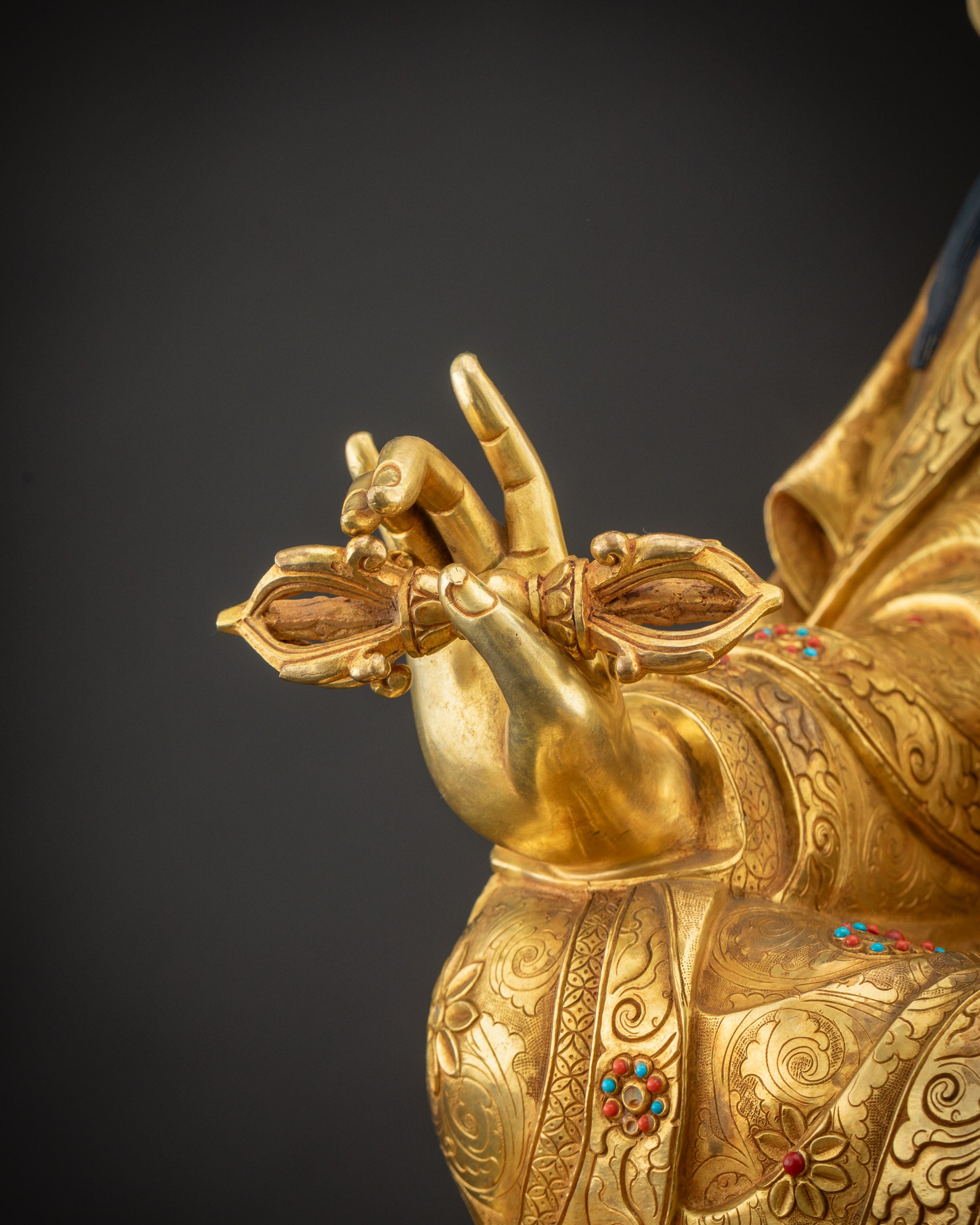 Detailed shot of Dorje vajra held by Guru Rinpoche with gold and jewels
