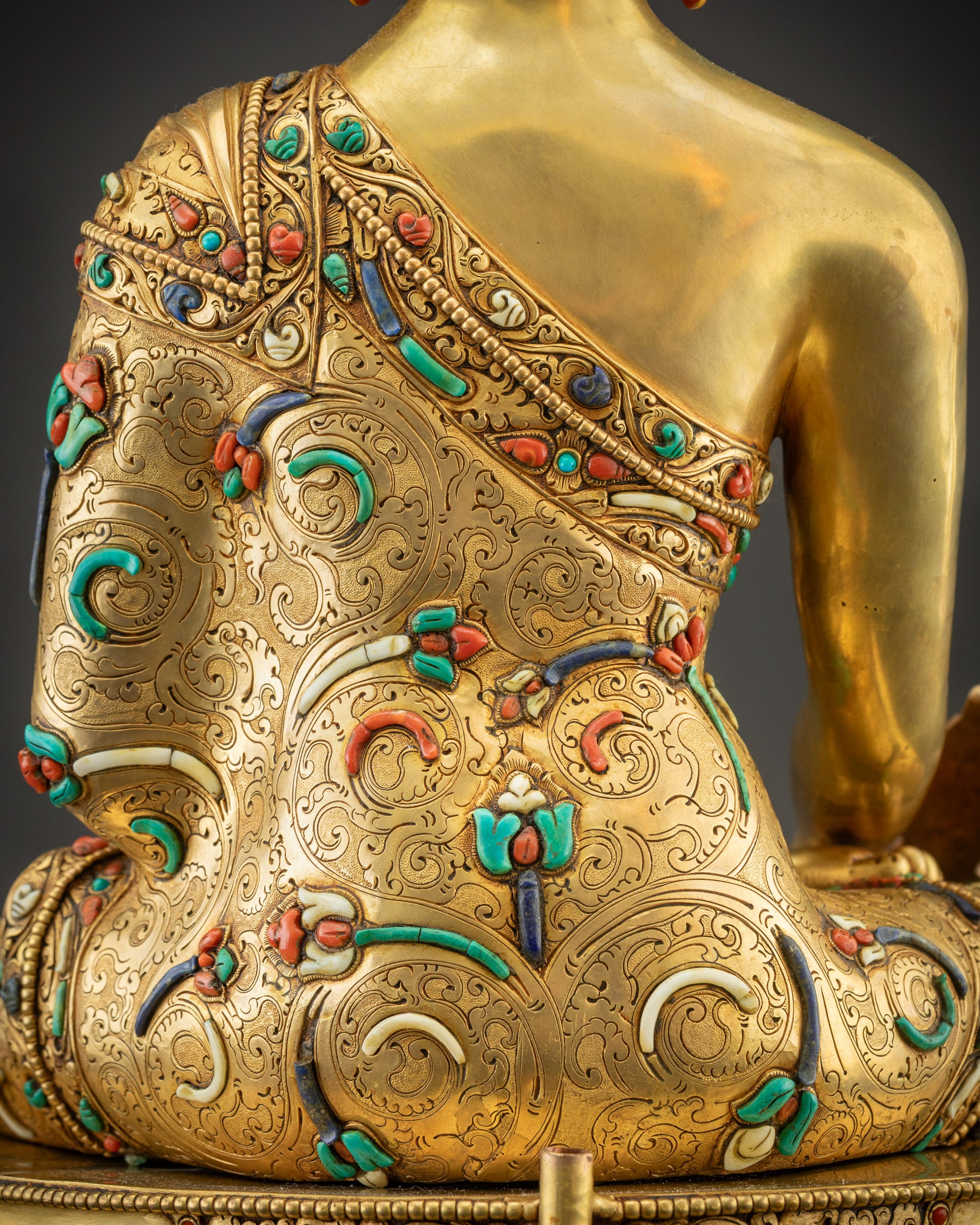 Detailed shot of carved robe patterns of Medicine Buddha with filigree, gold texture, and stones