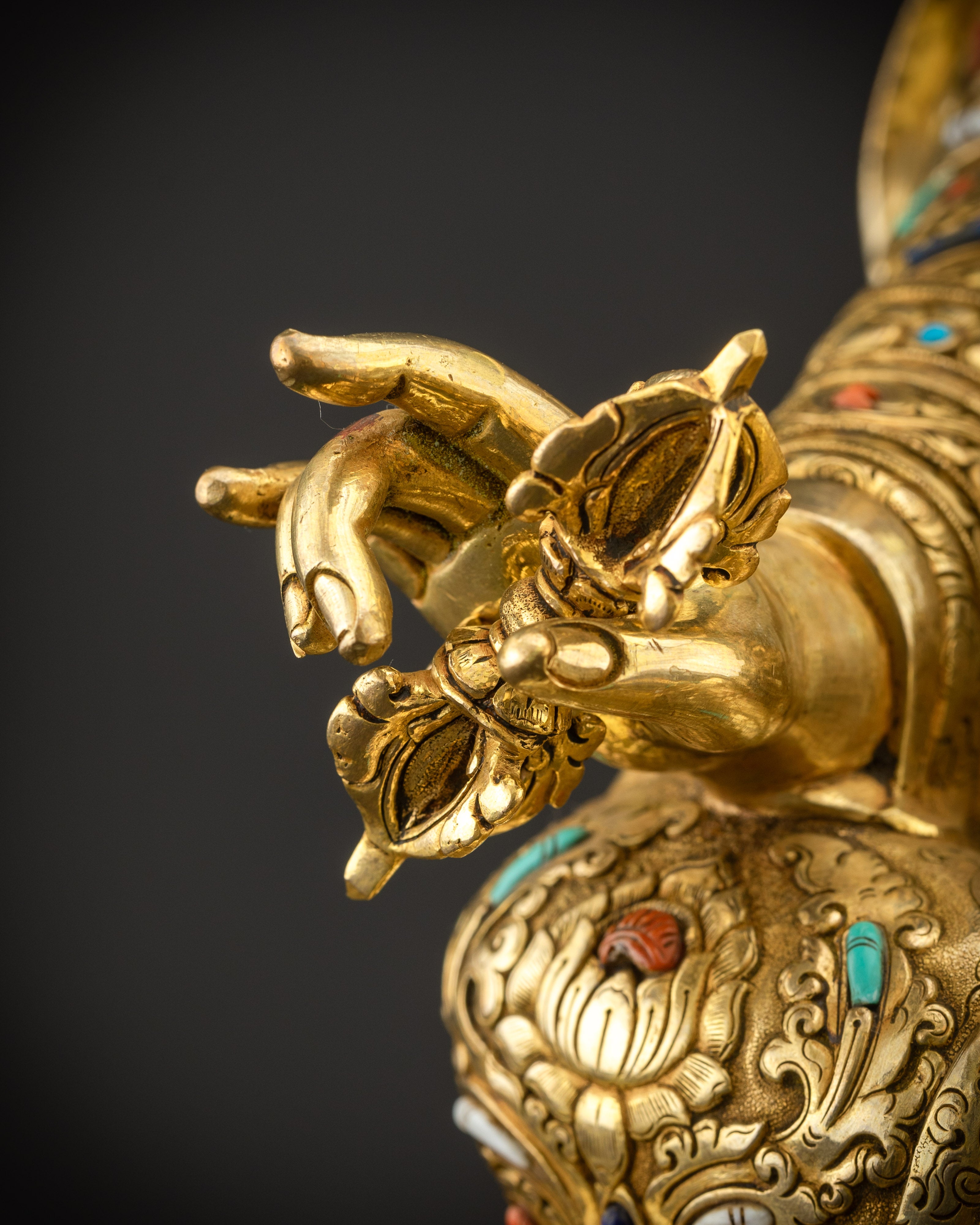 Detailed shot of vajra in right hand emphasizing gold gilding and sacred symbolism
