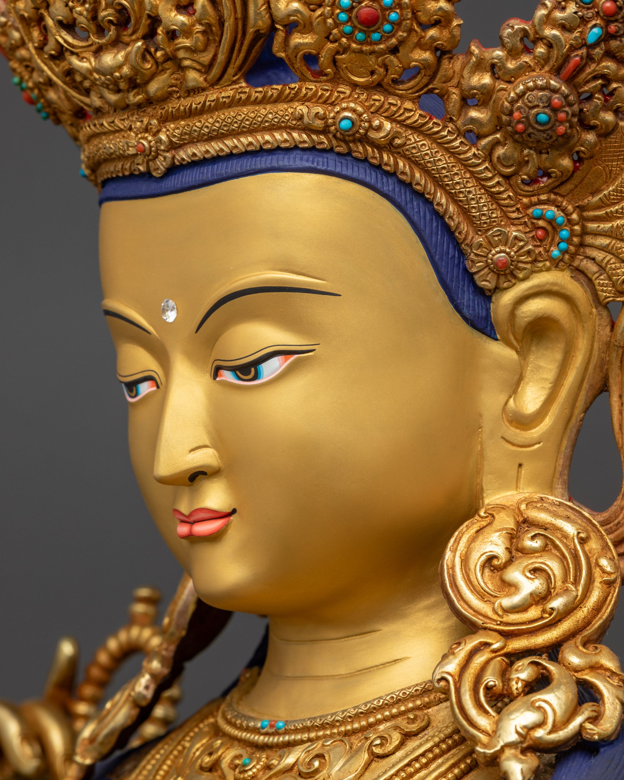 Detailed side close up face Chenrezig statue peaceful expression and semi-precious stones