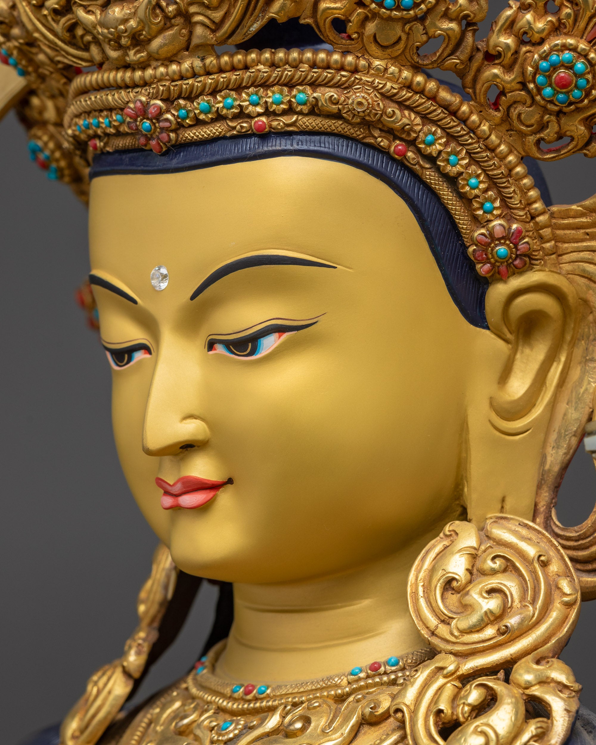 Detailed side close up face of Manjushri Sculpture with serene gold-gilded expression
