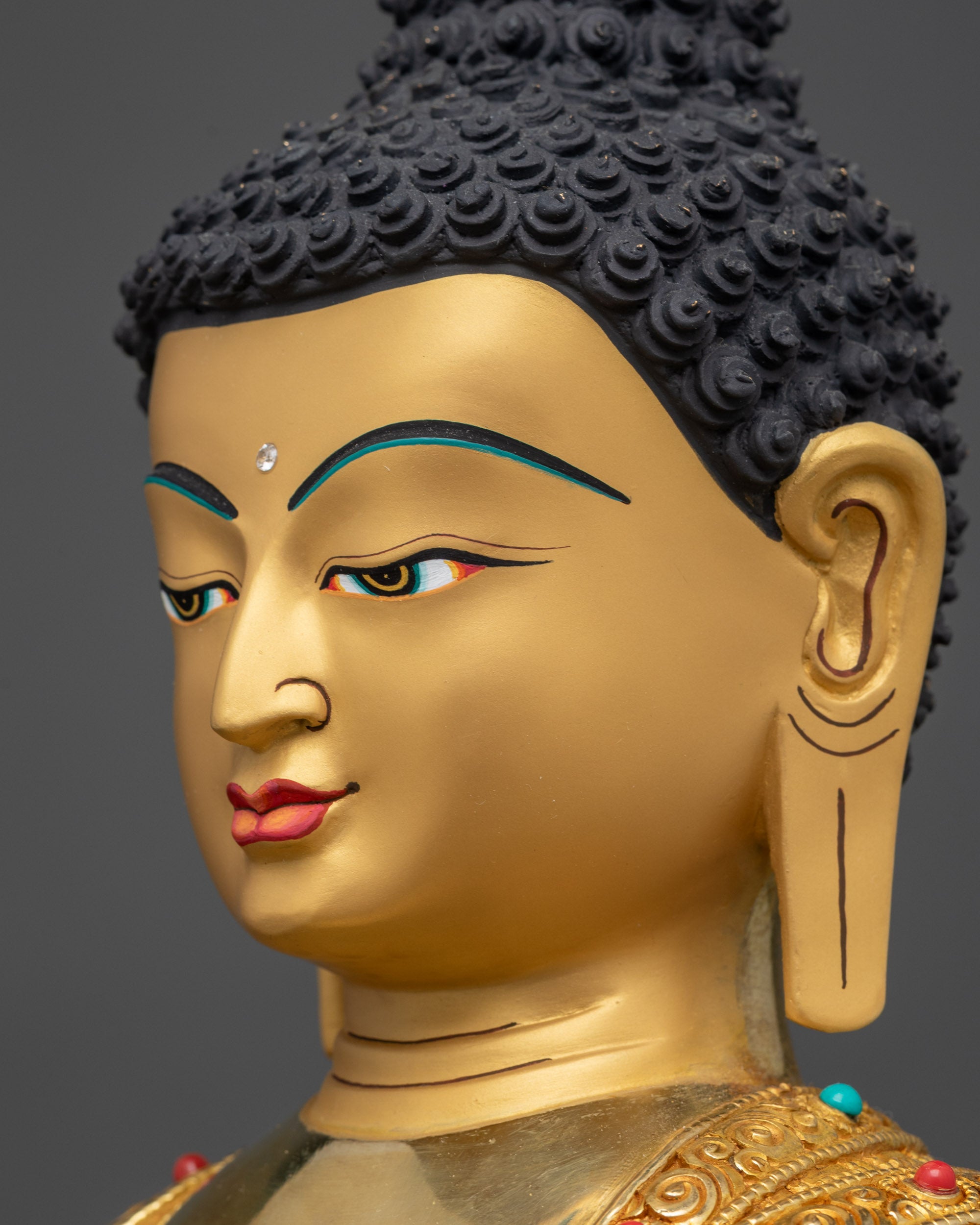 Detailed side close up face of Shakyamuni Buddha statue with turquoise and coral inlays
