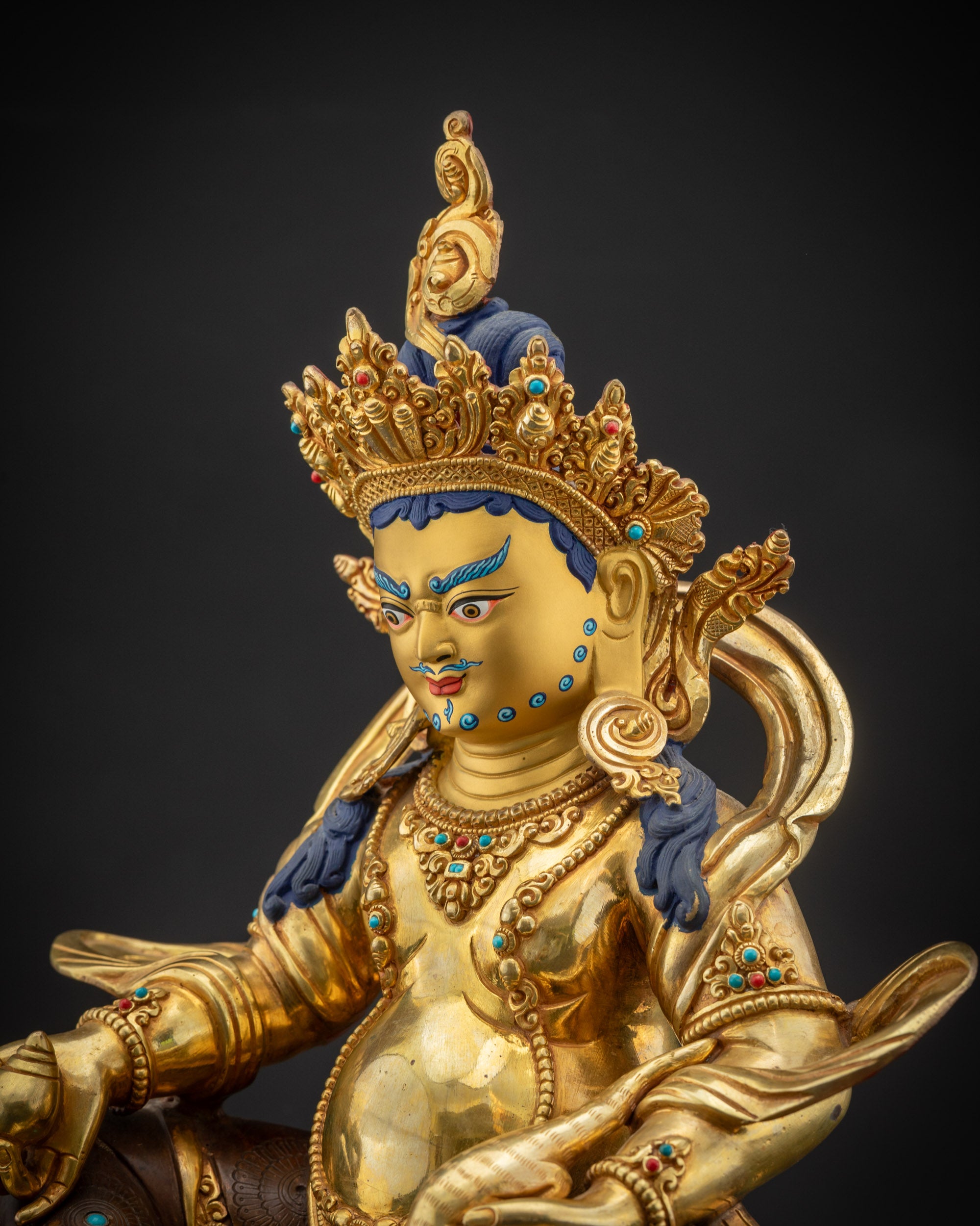 Detailed side view Dzambhala statue swirling garments and gold-gilded upper body