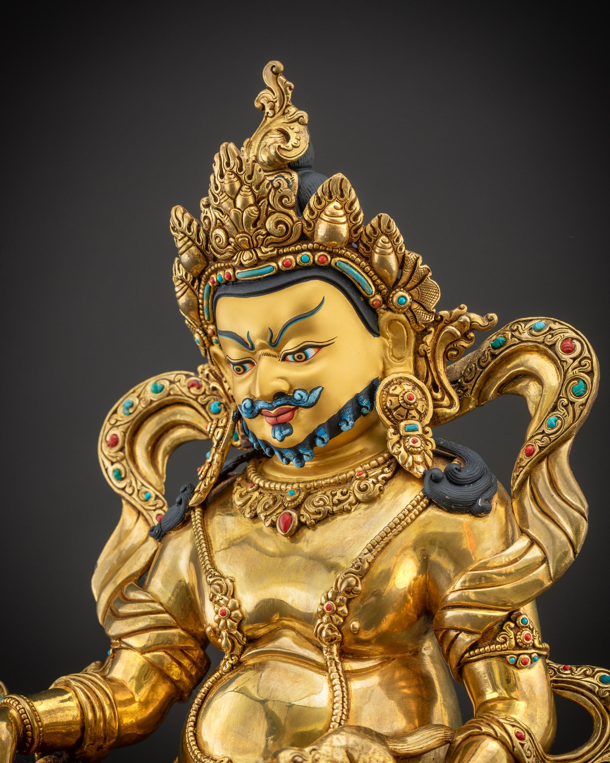 Detailed side view of Dzambhala statue showing swirling garments and semi-precious stones
