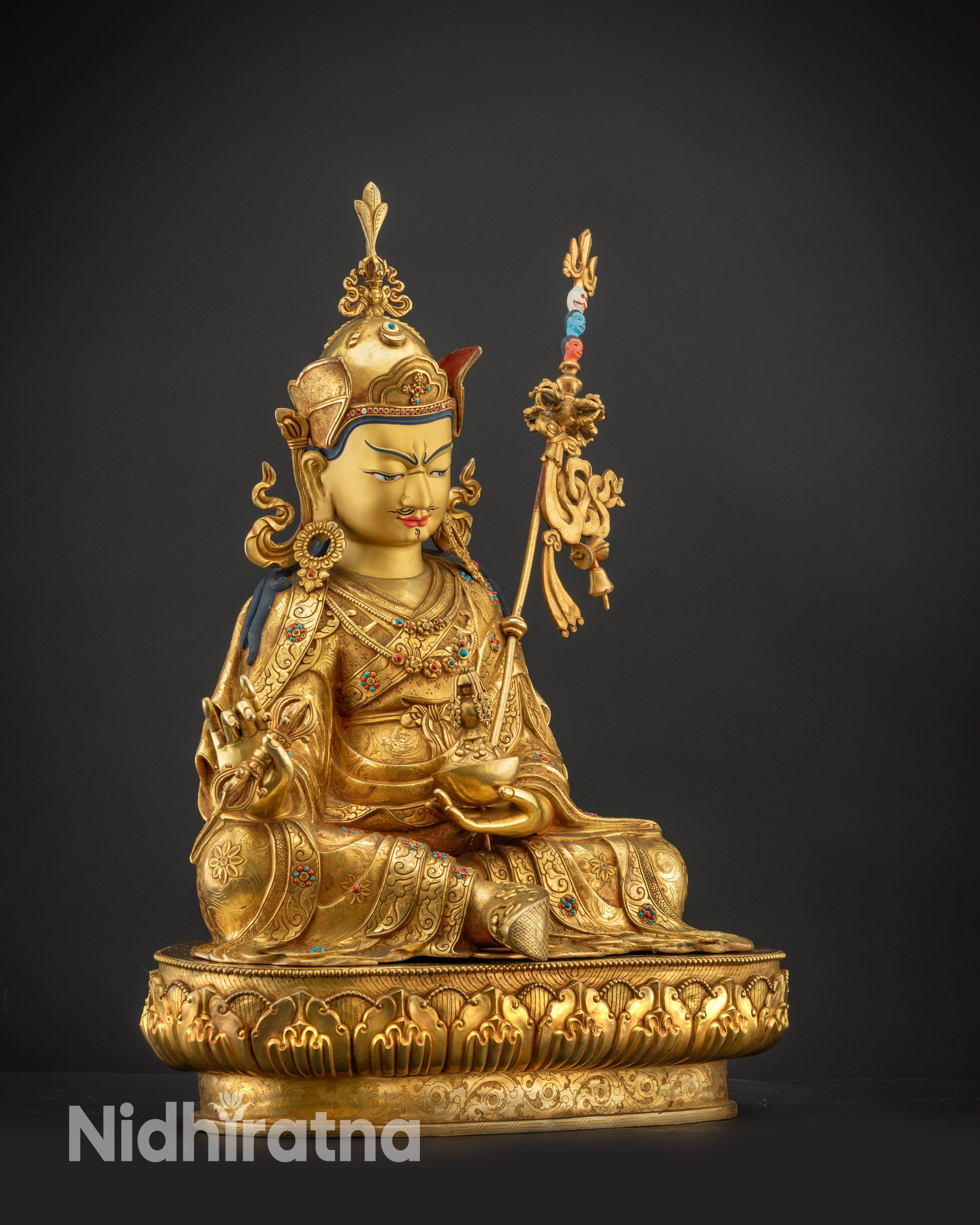 Detailed side view of Guru Rinpoche holding vajra and khatvanga staff
