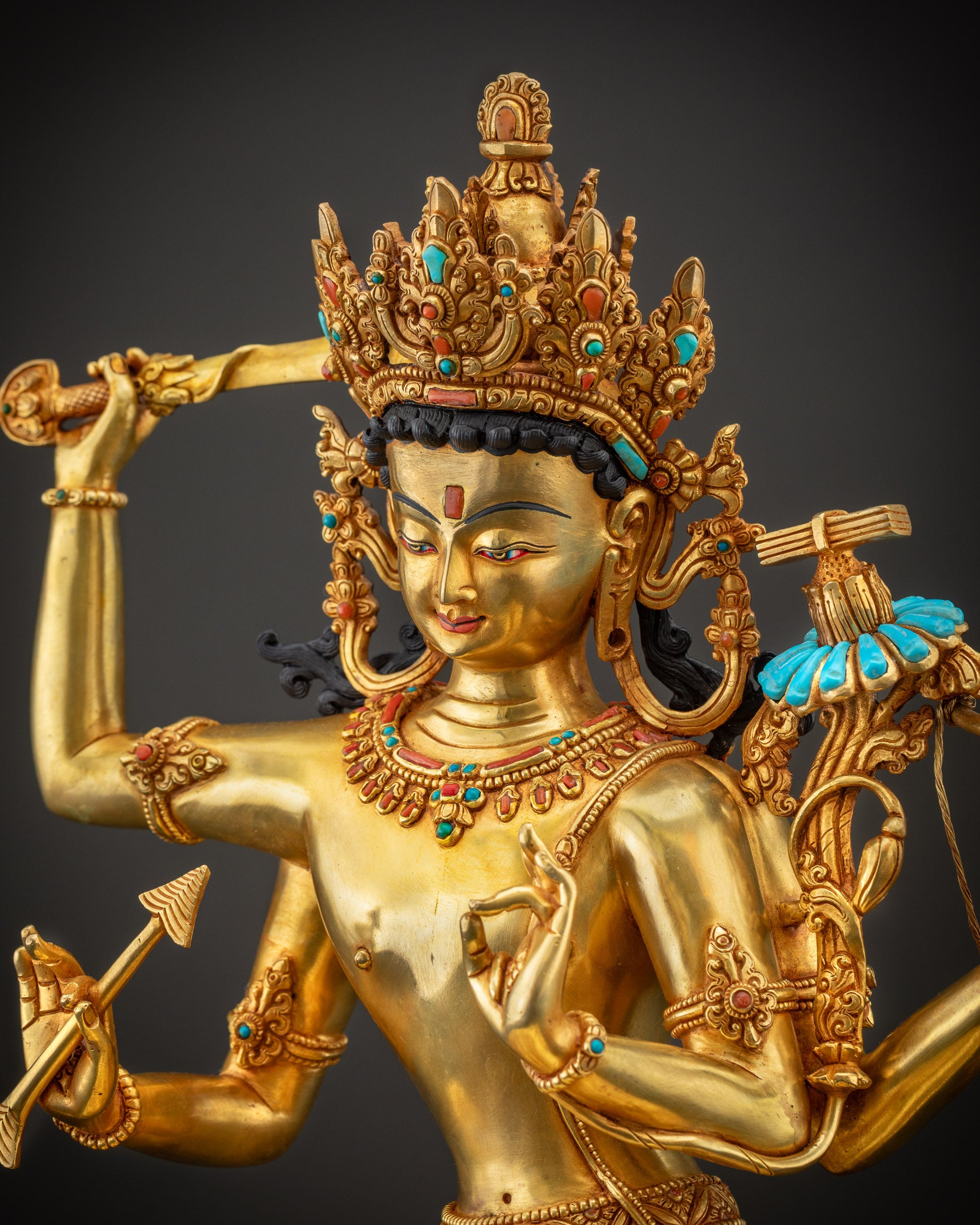 Detailed side view of Maha Manjushri statue showing ornate robe, jewelry, and golden textures.
