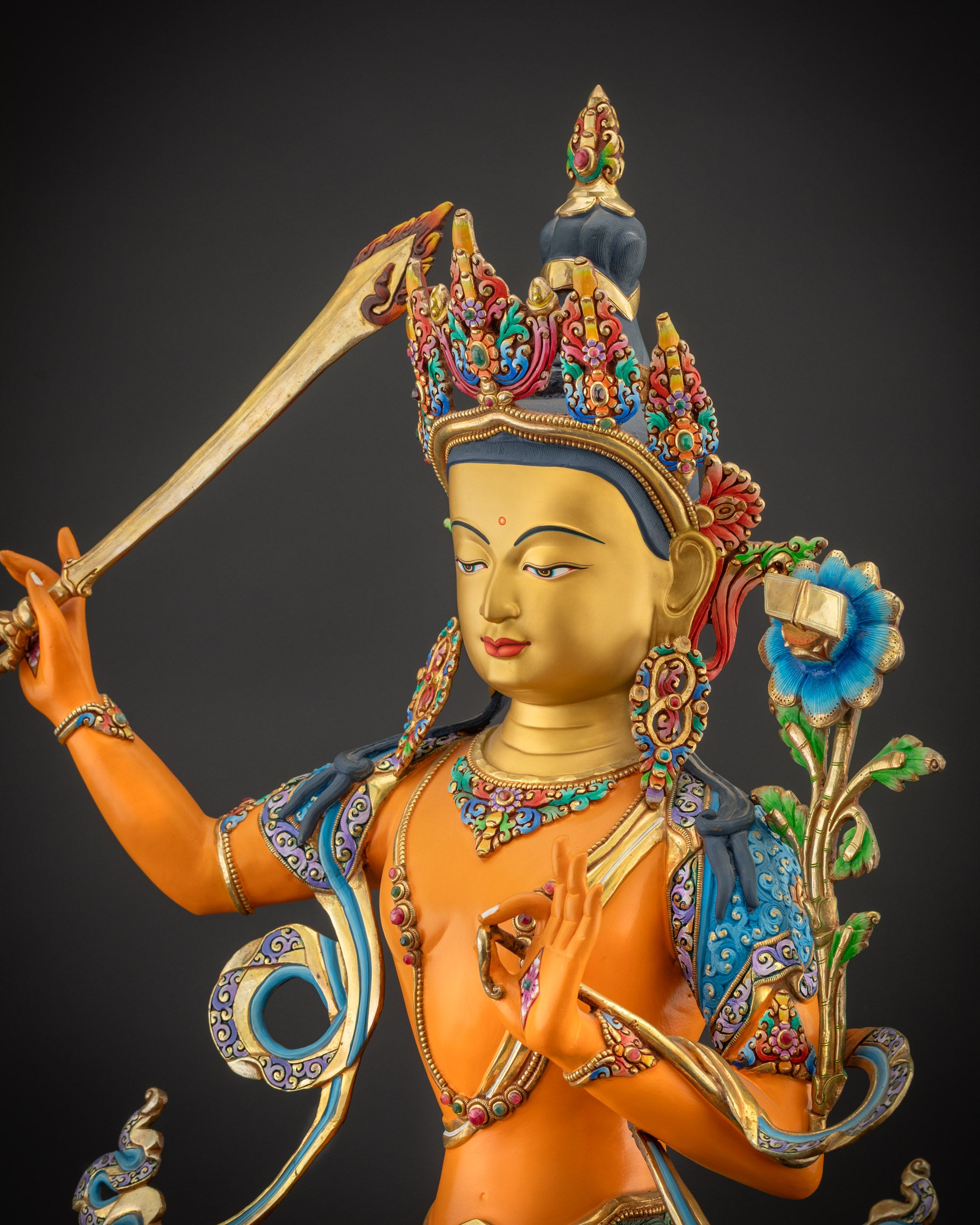 Detailed side view of Manjushri statue with semi-precious stones and carved lotus base
