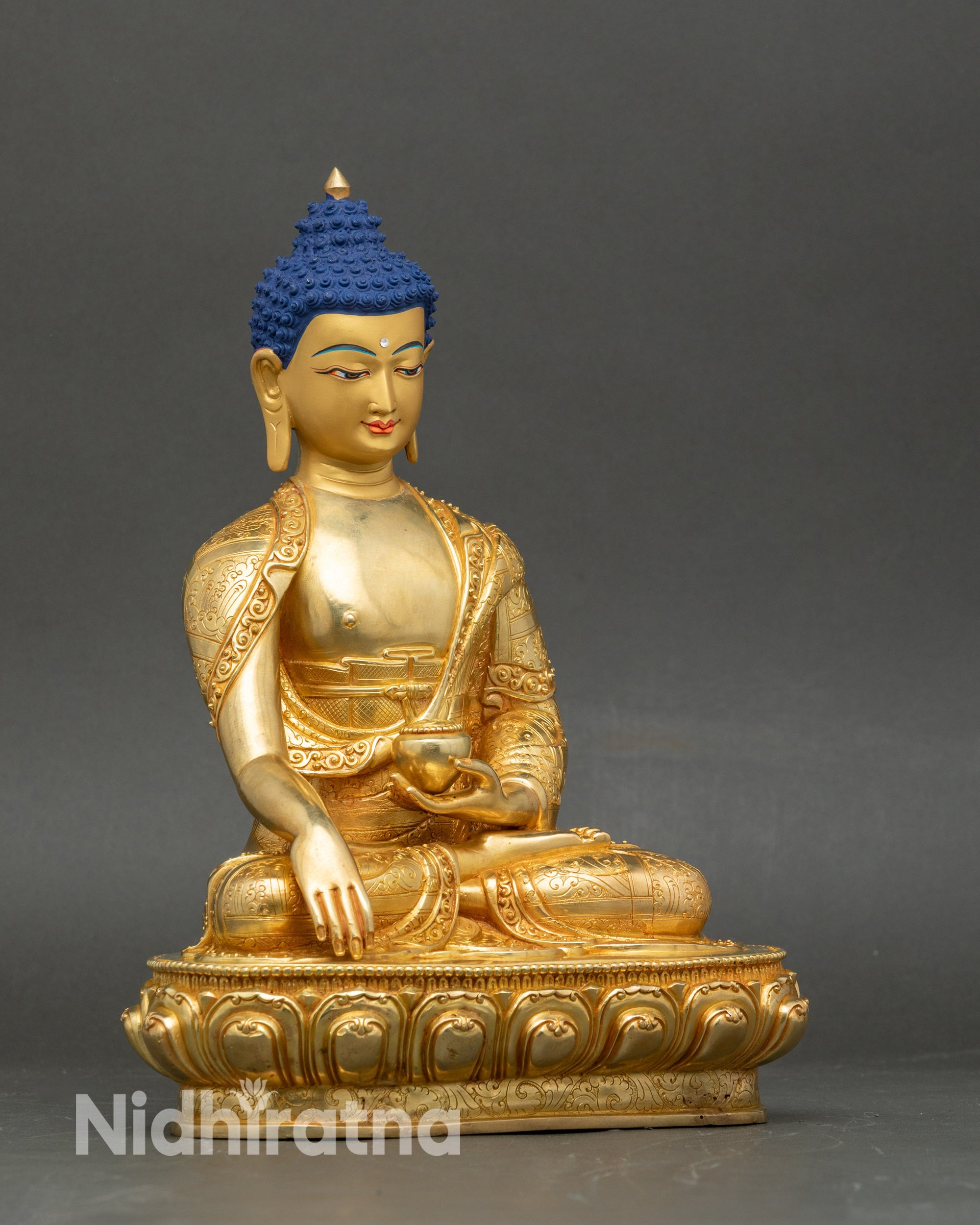 Detailed side view of Shakyamuni Buddha holding patra bowl, copper and gold artwork