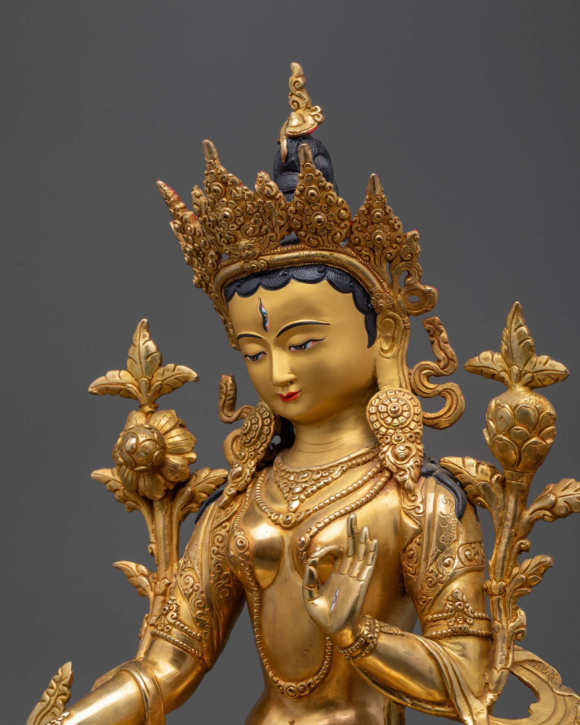 Detailed side view of White Tara Statue holding utpala flower in varada mudra
