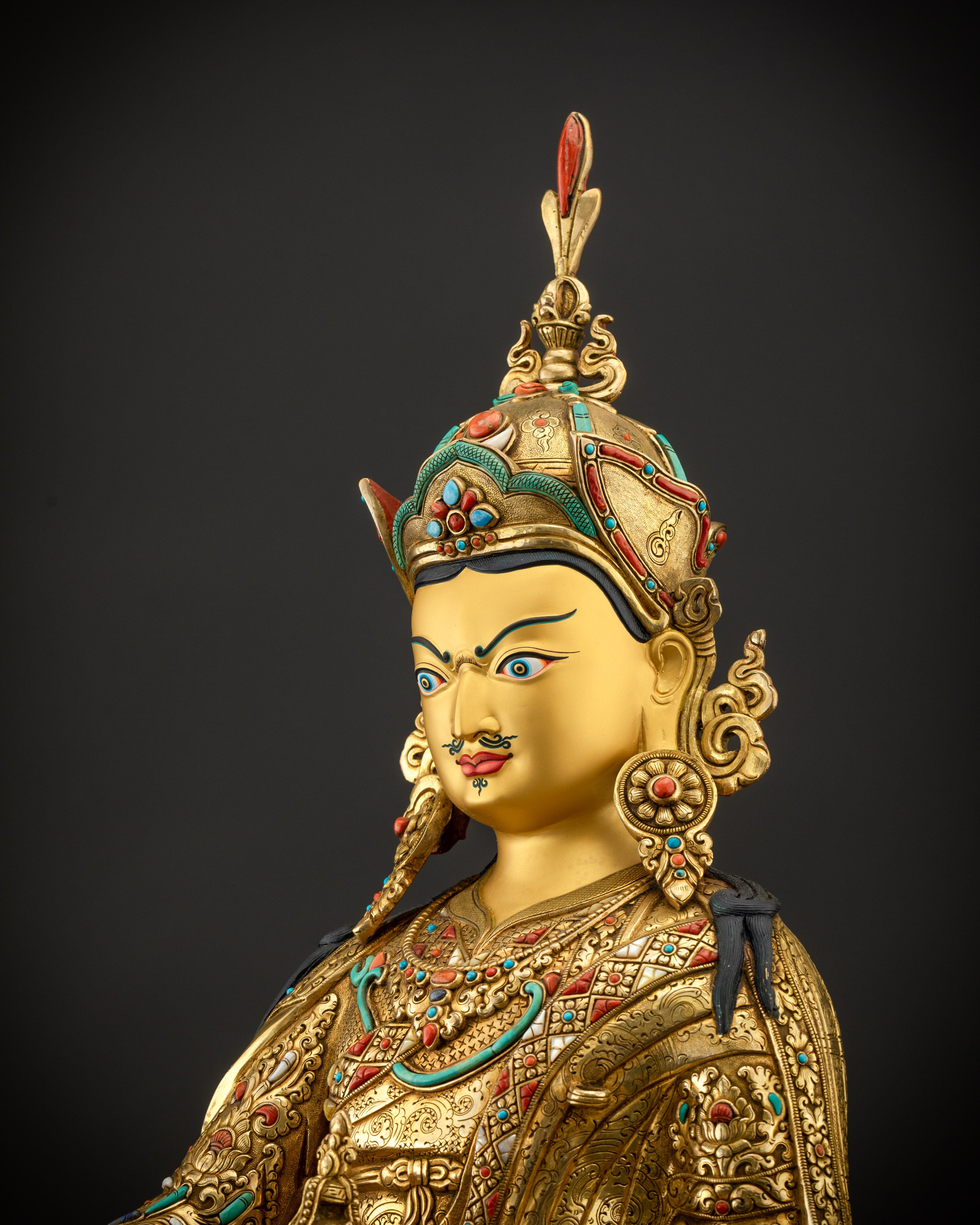 Detailed side view of statue showing lotus hat, feather, and five-petal crown
