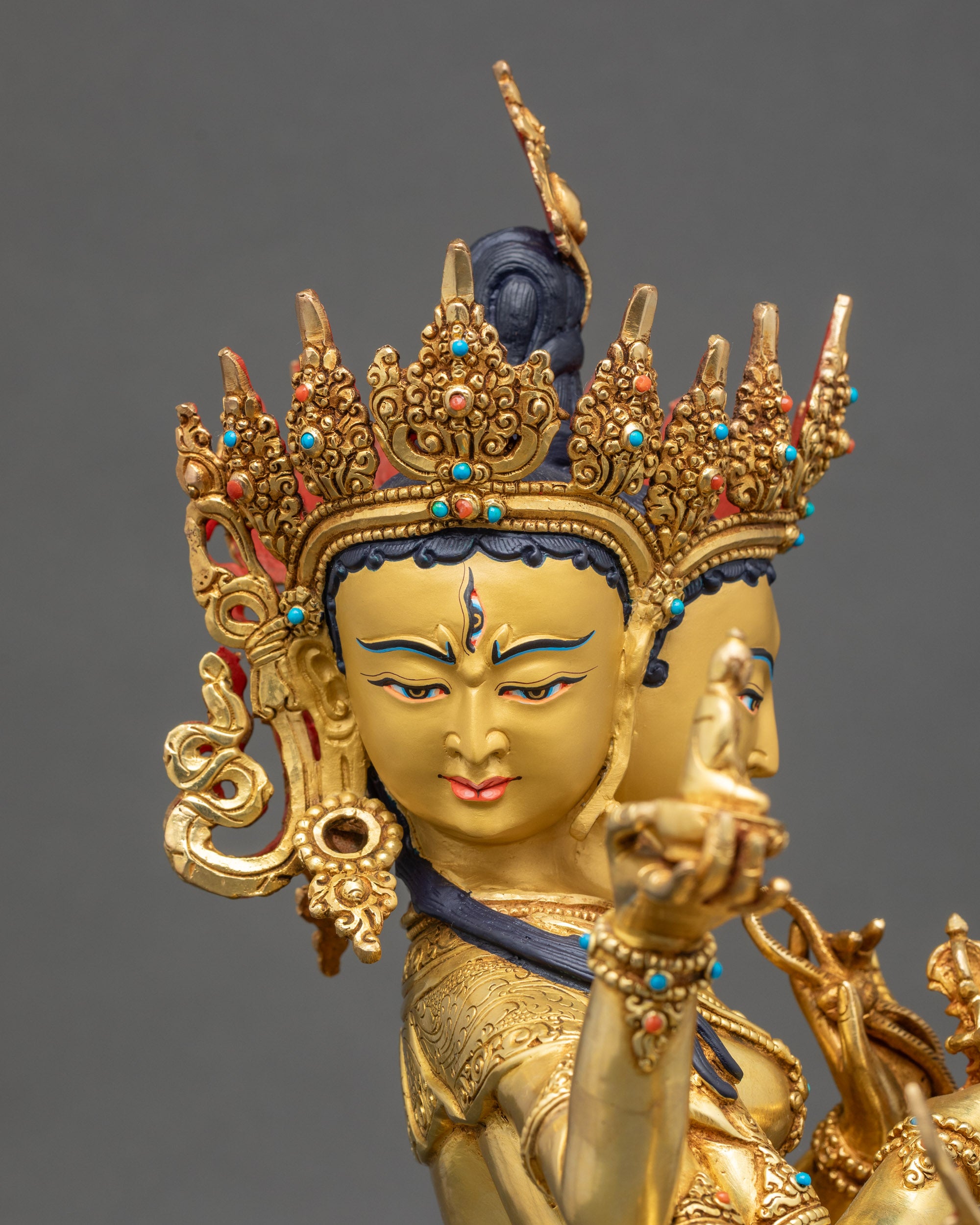 Detailed view of three gold-gilded faces on Namgyalma Ushnisha Vijaya statue with ornate crown