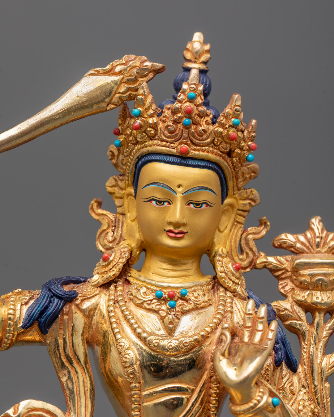 Double-edged sword and Utpala flower in Vitarka Mudra, close-up of Manjushri sculpture details