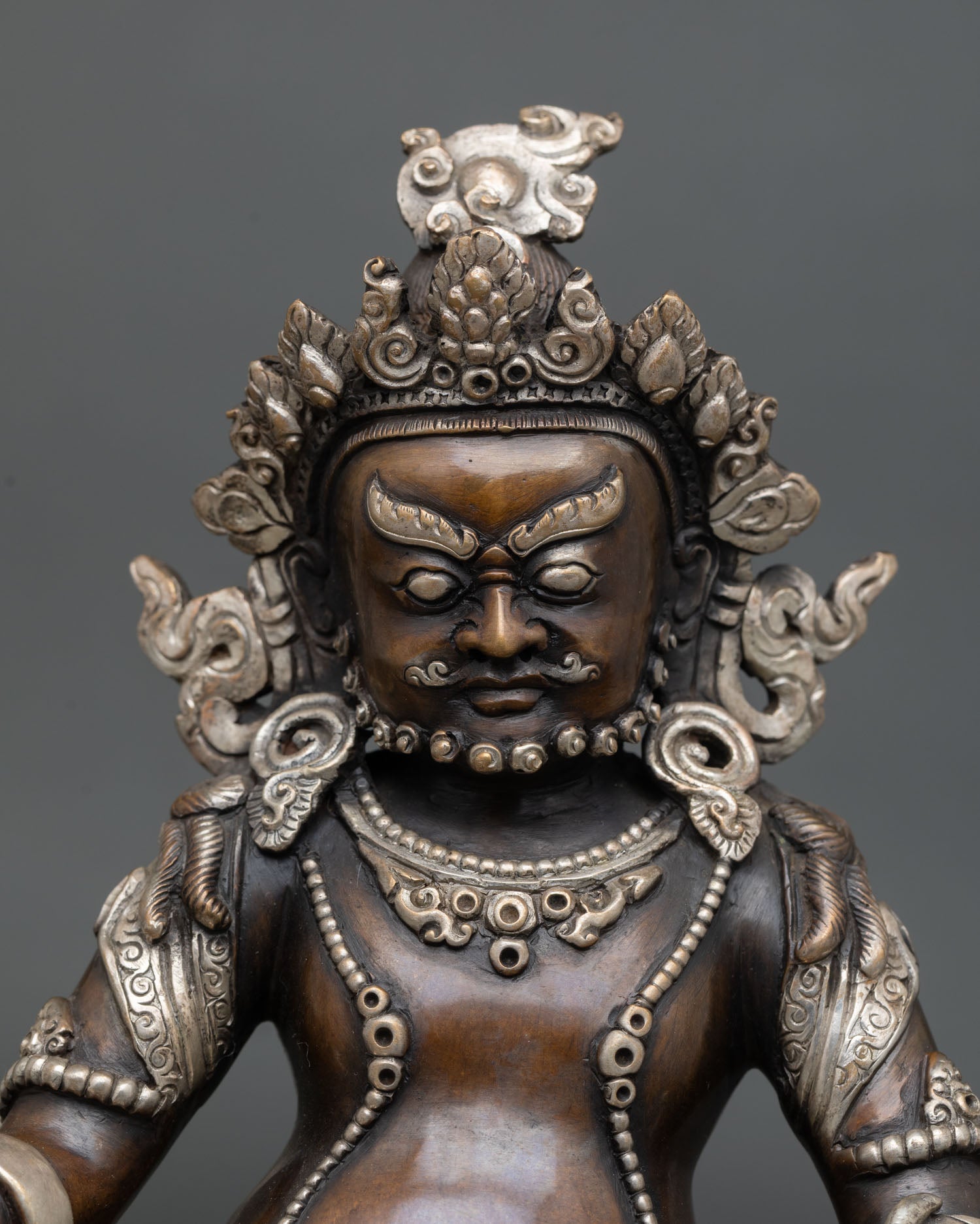 Dzambhala statue close up, silver plated copper detail, ornate repoussé art