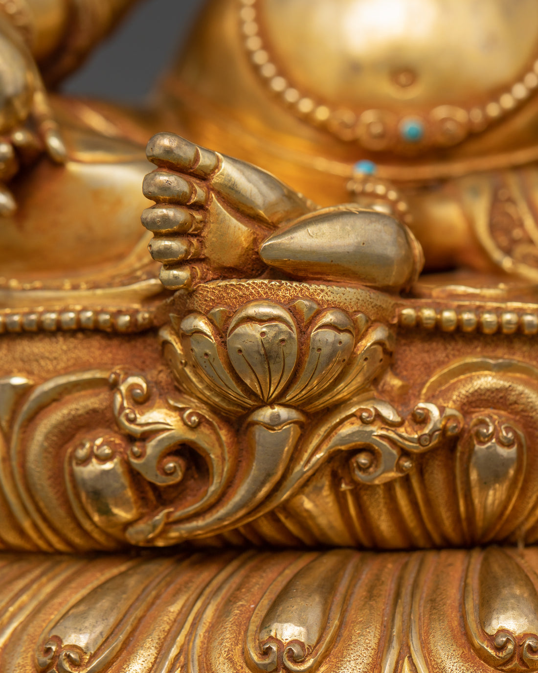 Close-up view of Dzambhala's right leg, showcasing its relaxed and majestic posture atop a lotus base