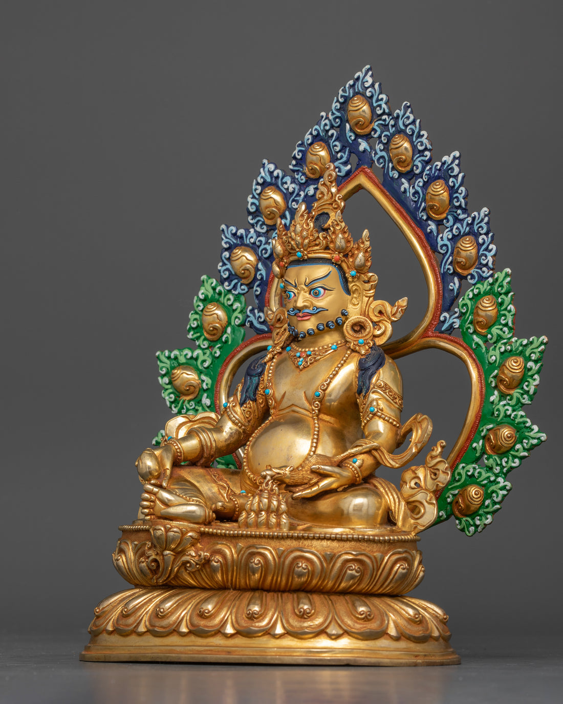 Left side view of a Dzambhala statue, showcasing the deity seated on a lotus base, holding a mongoose.