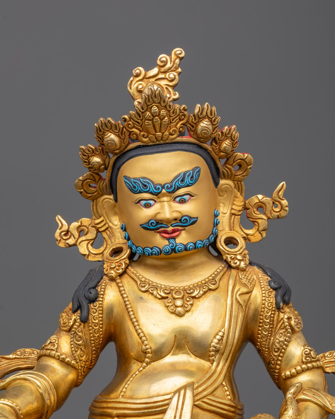 Dzambhala Statue closeup showing crown, jewelry-spitting mongoose, and crayon fruit