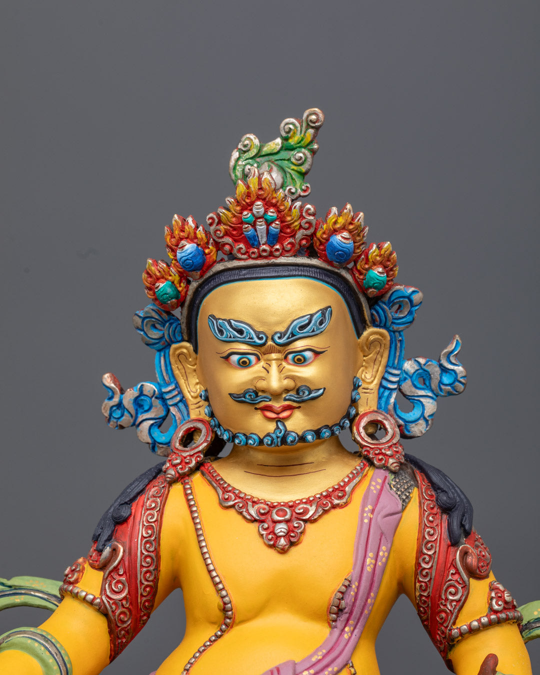 Dzambhala sculpture seated in royal ease on a lotus throne with citron fruit and jewel-spitting mongoose representing prosperity