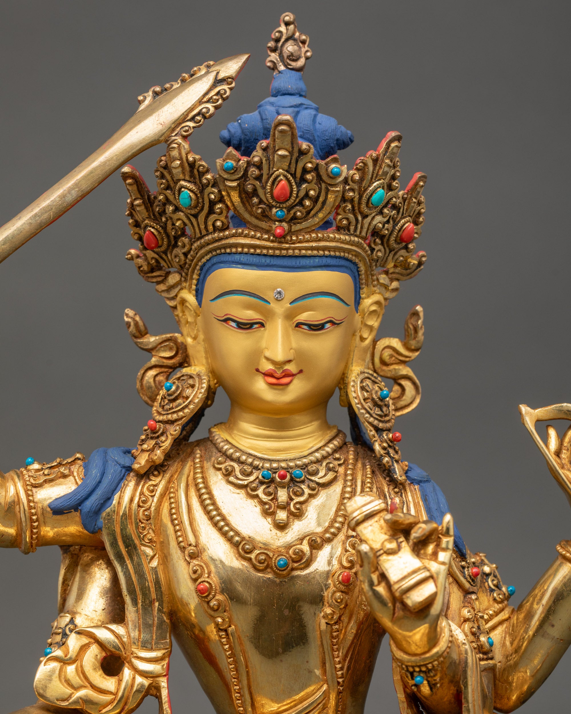 Detailed close-up of Manjushri Statue face | Nepalese Buddhist sculpture showing serene expression and gold fire-gilding