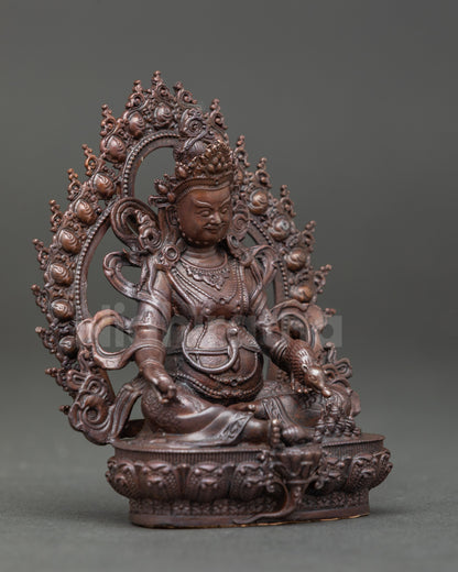 Side view of Dzambhala statue showing intricate details of lotus seat and deity posture