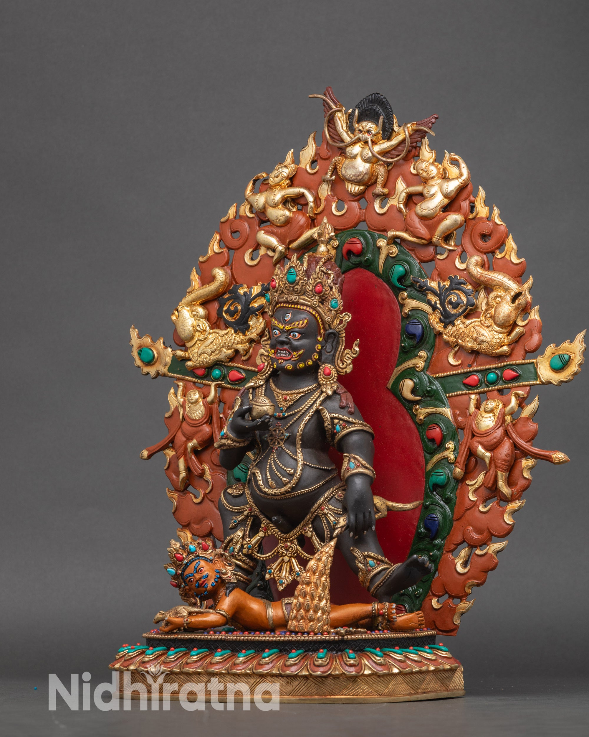 Left profile of Black Dzambhala statue with detailed kapala and mongoose figure