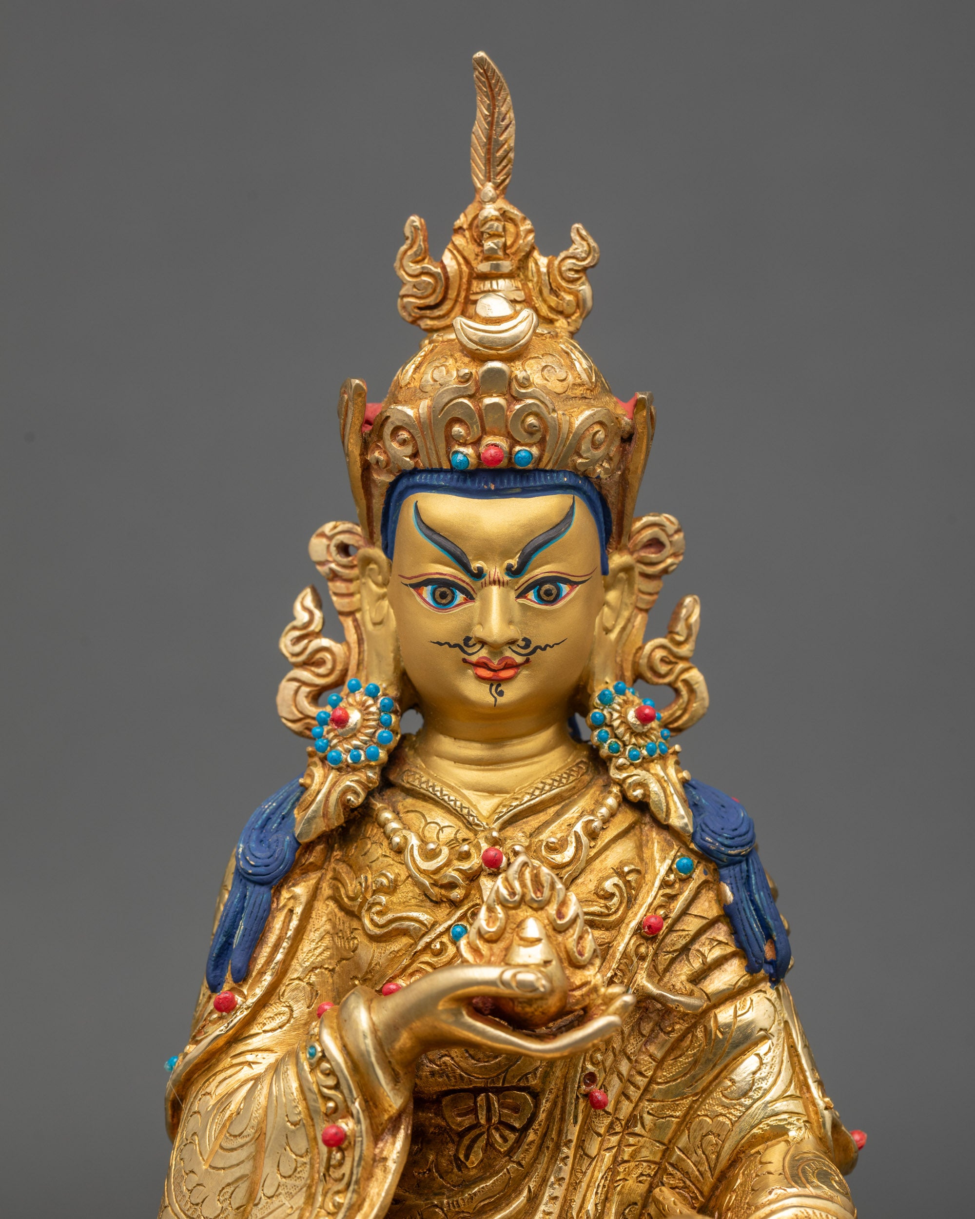 Close up Guru Norlha face, gold-painted expression with semi-precious stone details