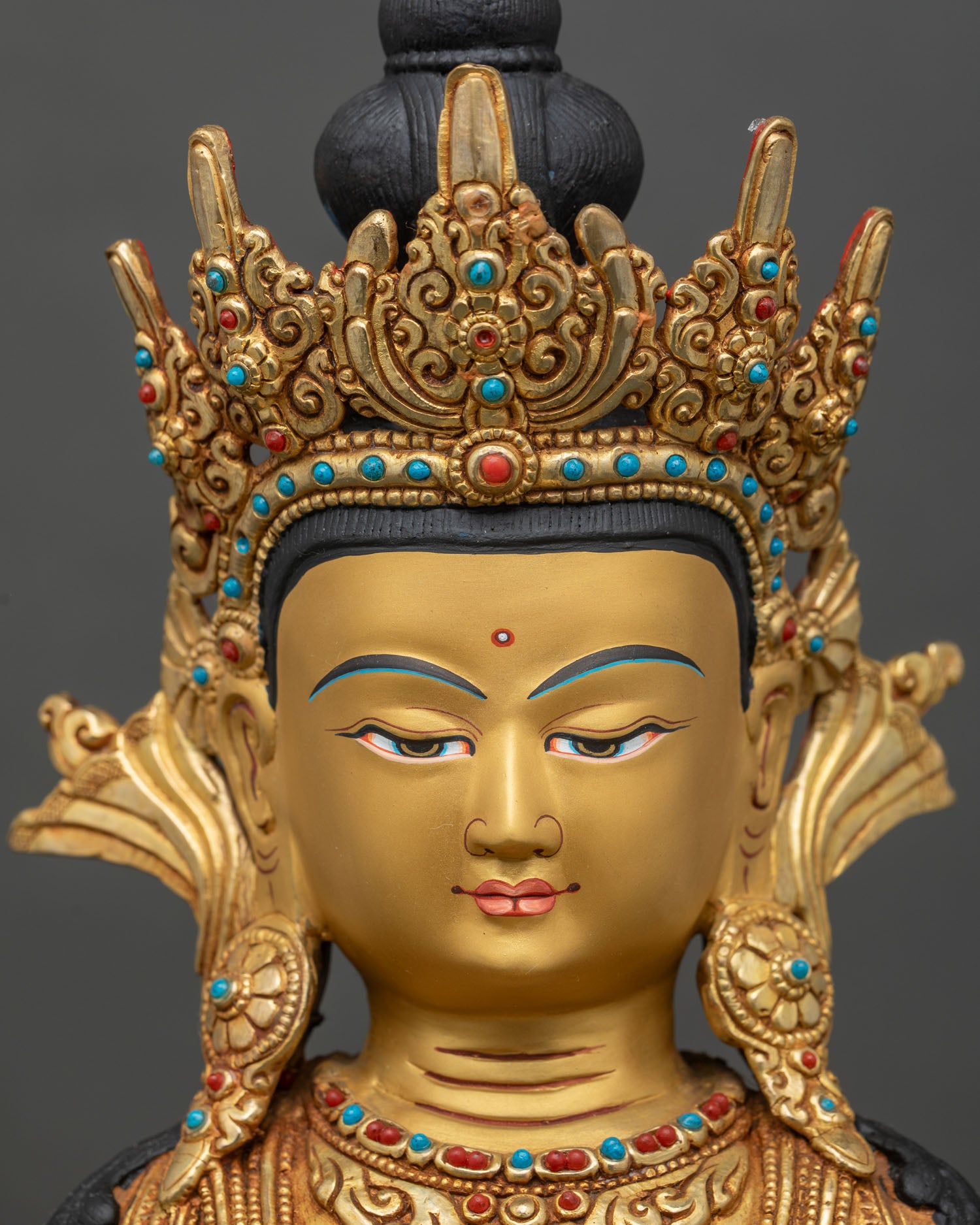 Face close-up of crowned Shakyamuni Buddha with gold-painted features and serene expression
