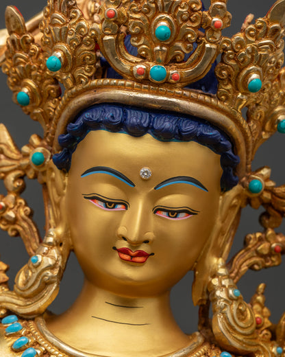 Face close-up of Maha Manjushri statue with serene gold-painted expression and crown details