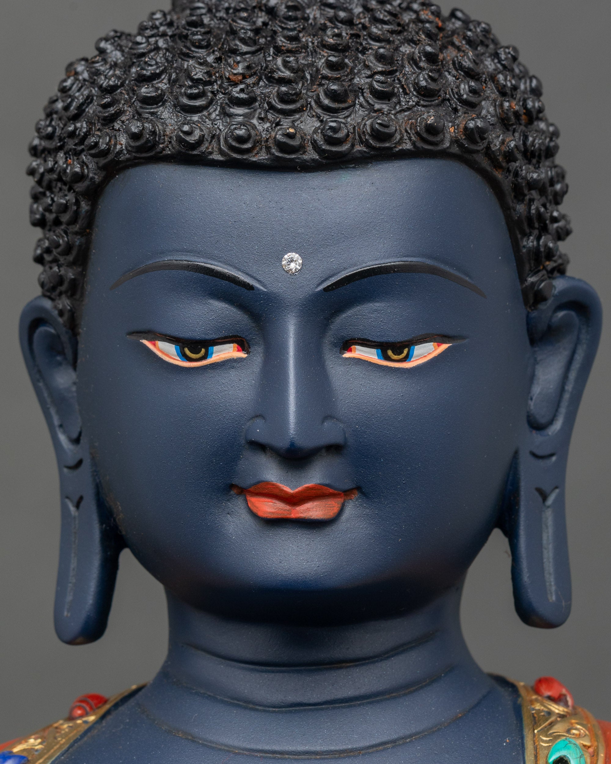 Face close-up of Bhaisajyaguru statue, peaceful expression with semi-precious stone accents